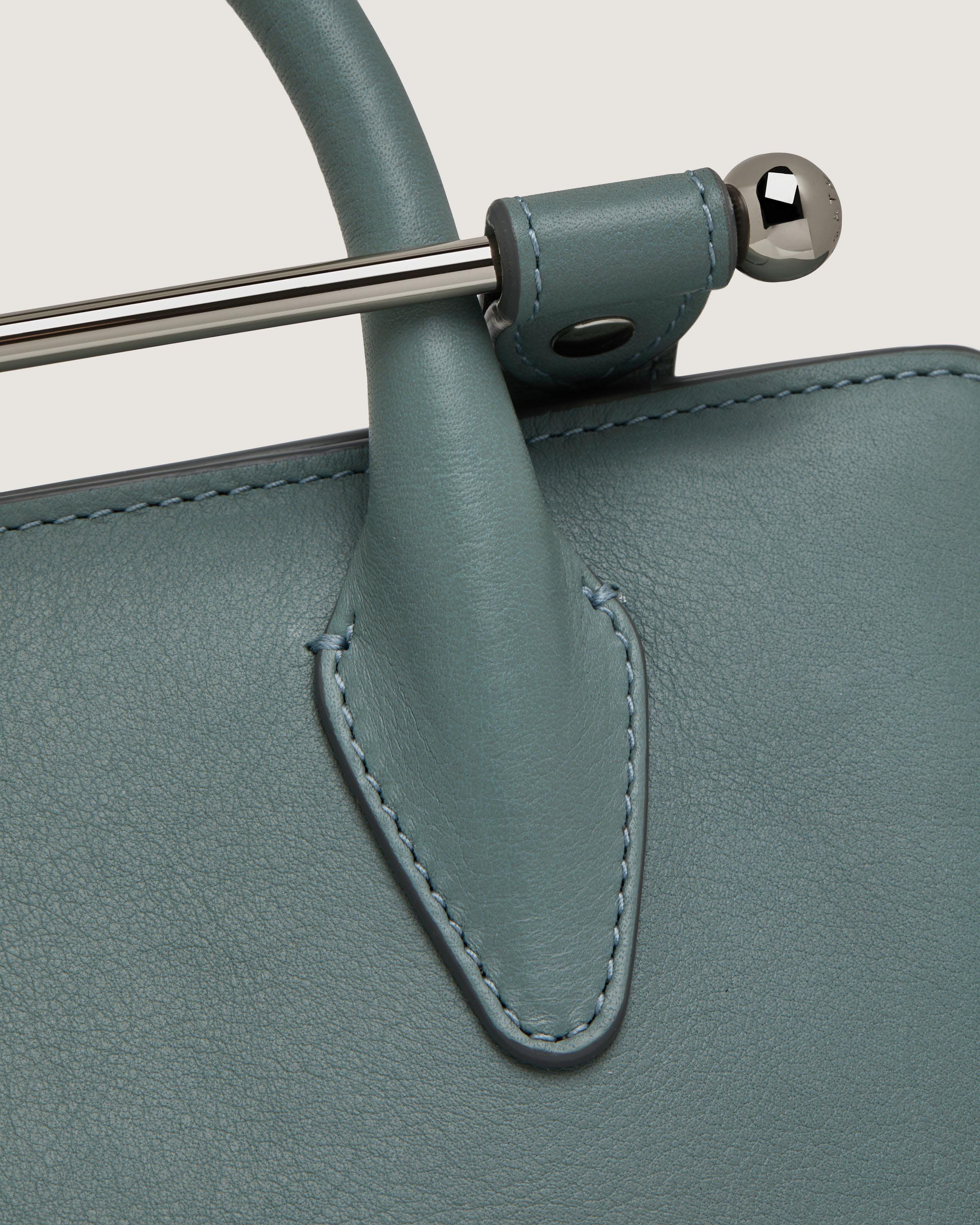 A close up of a green purse with a metal handle