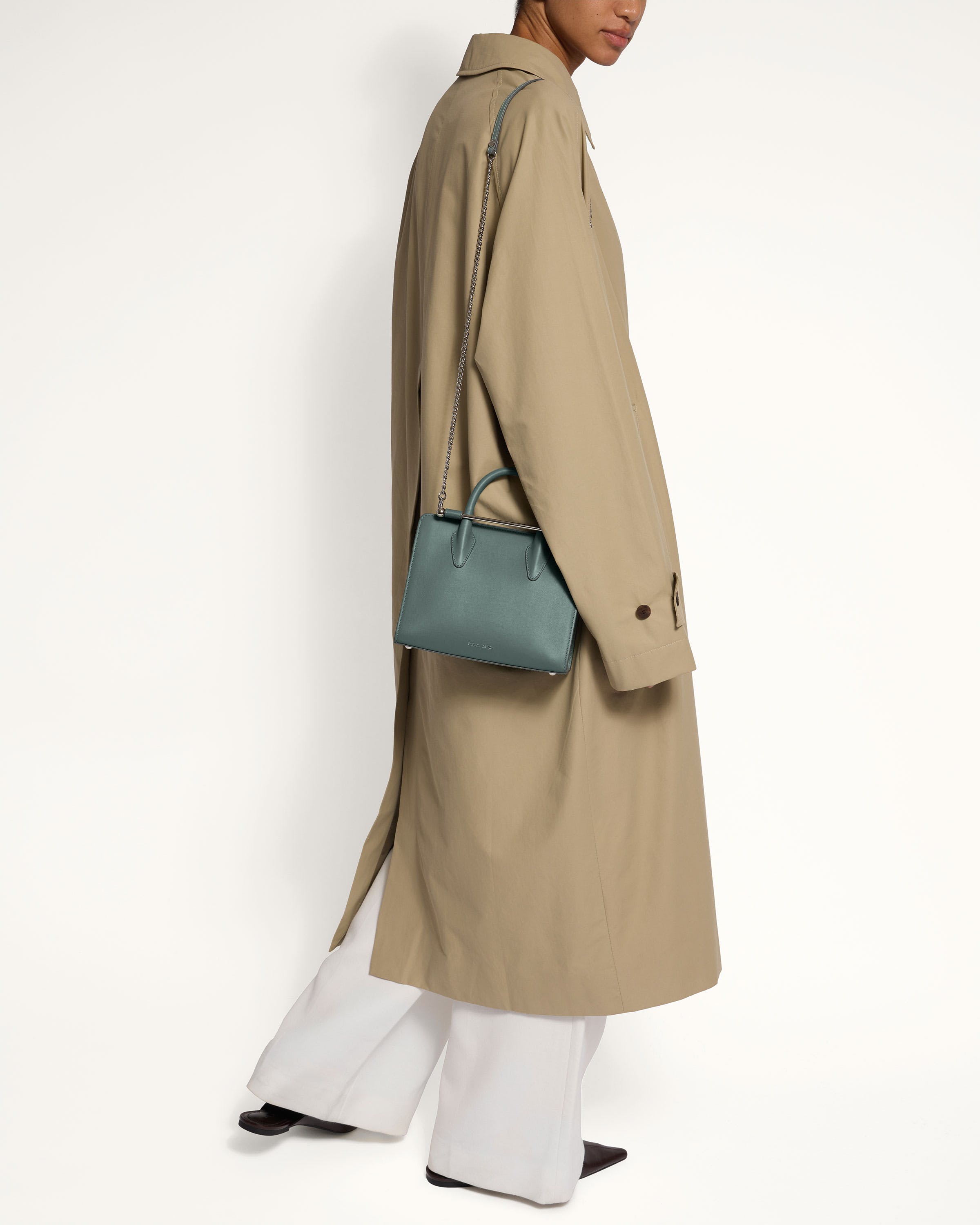 A woman in a trench coat carrying a blue handbag