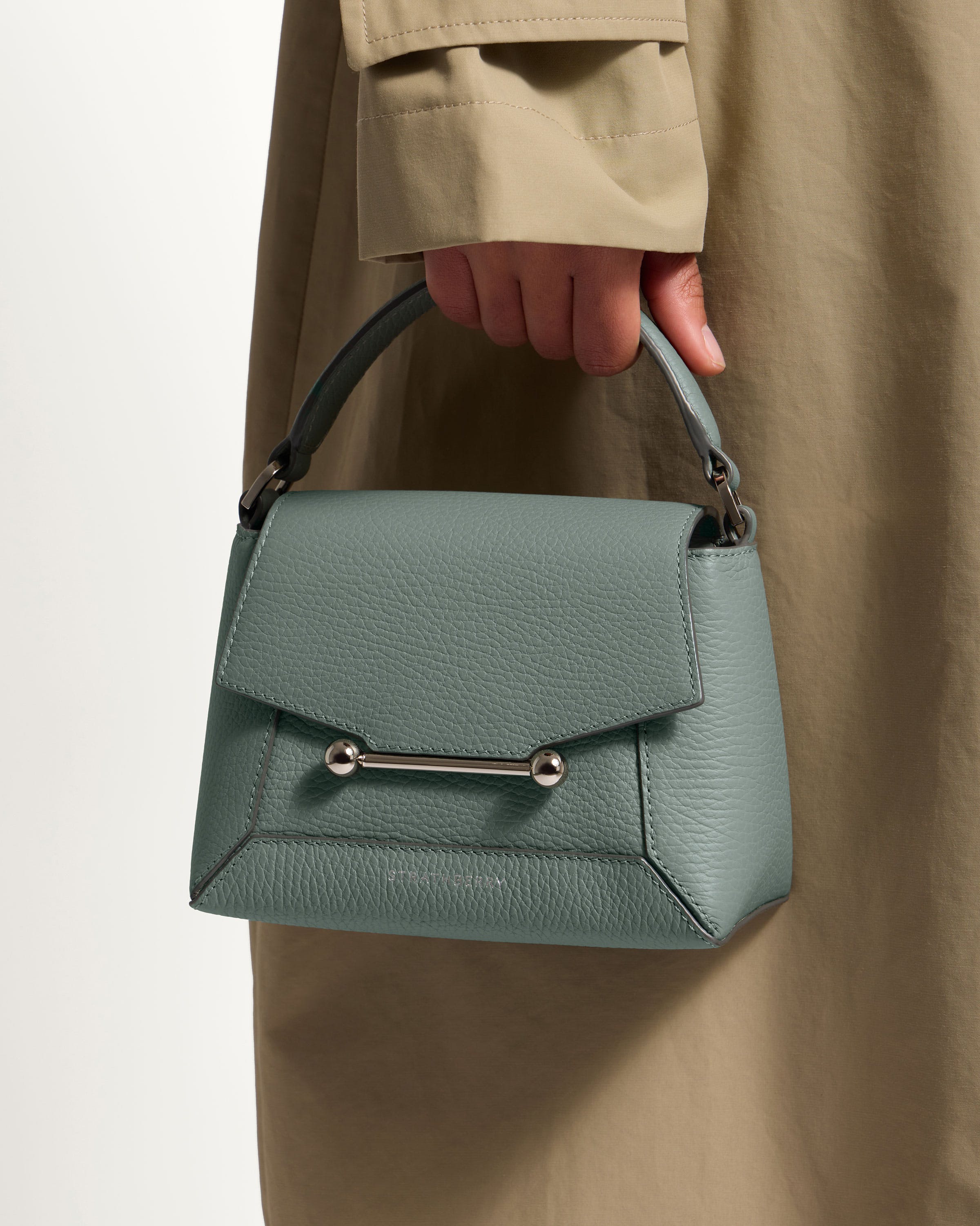 A woman is holding a green handbag