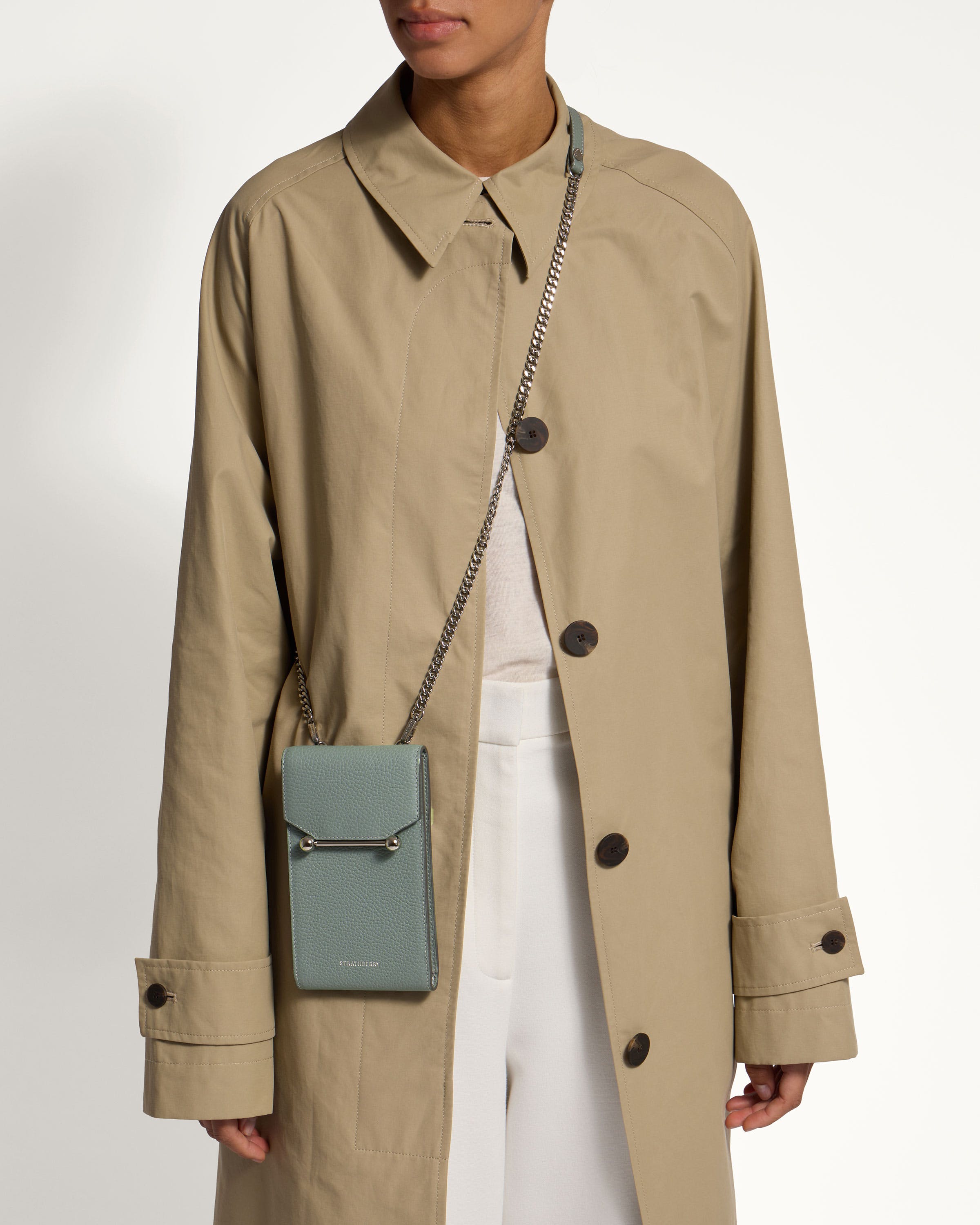 A woman in a trench coat holding a small purse