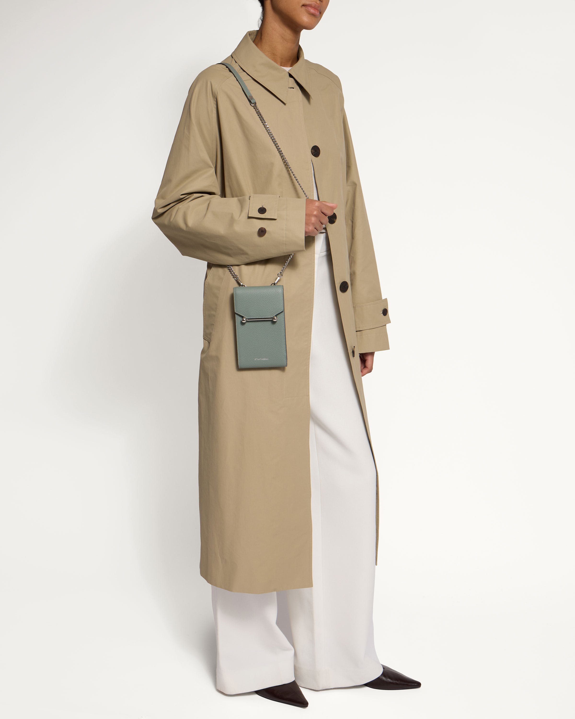 A woman wearing a trench coat and white pants