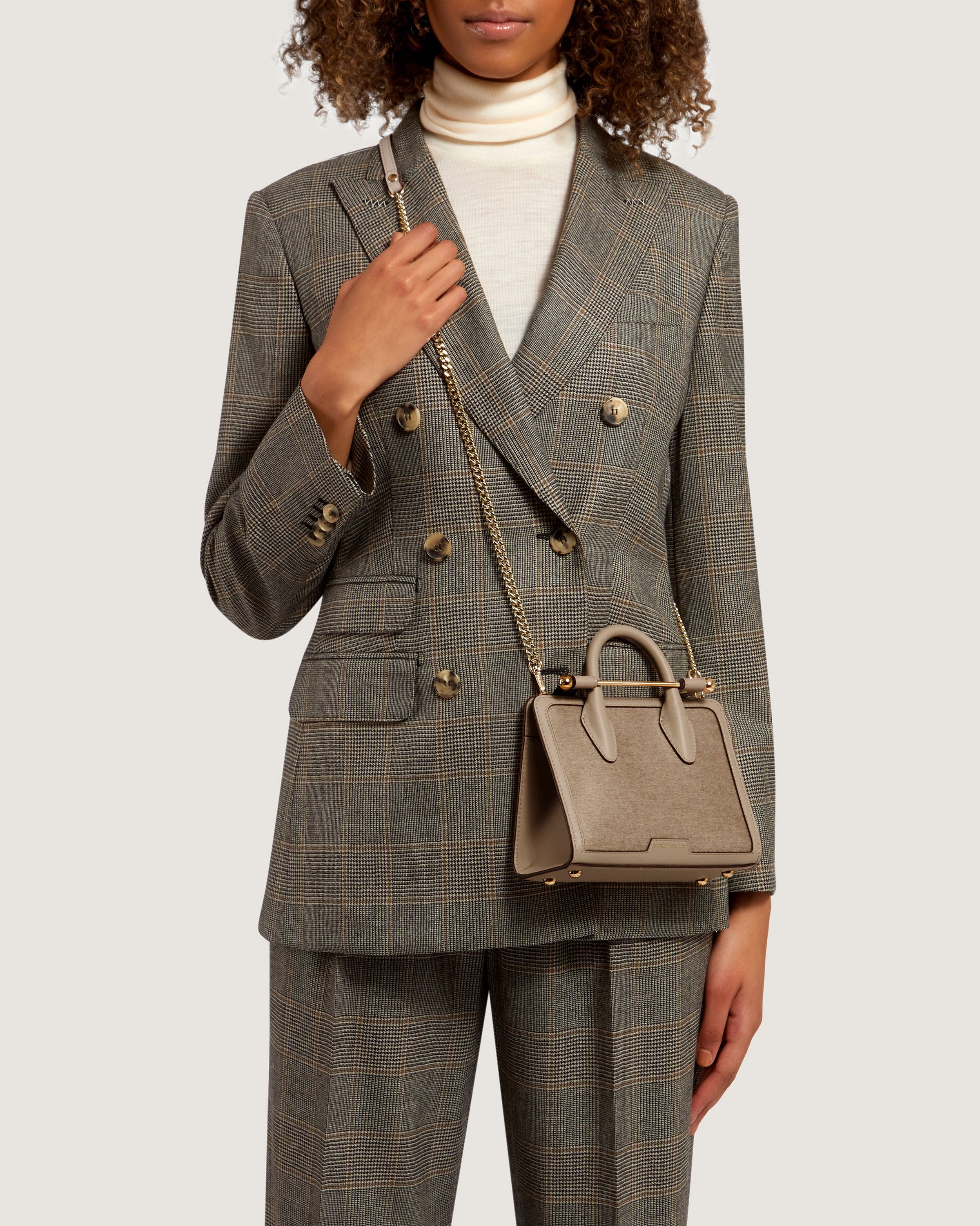 A woman in a suit holding a handbag