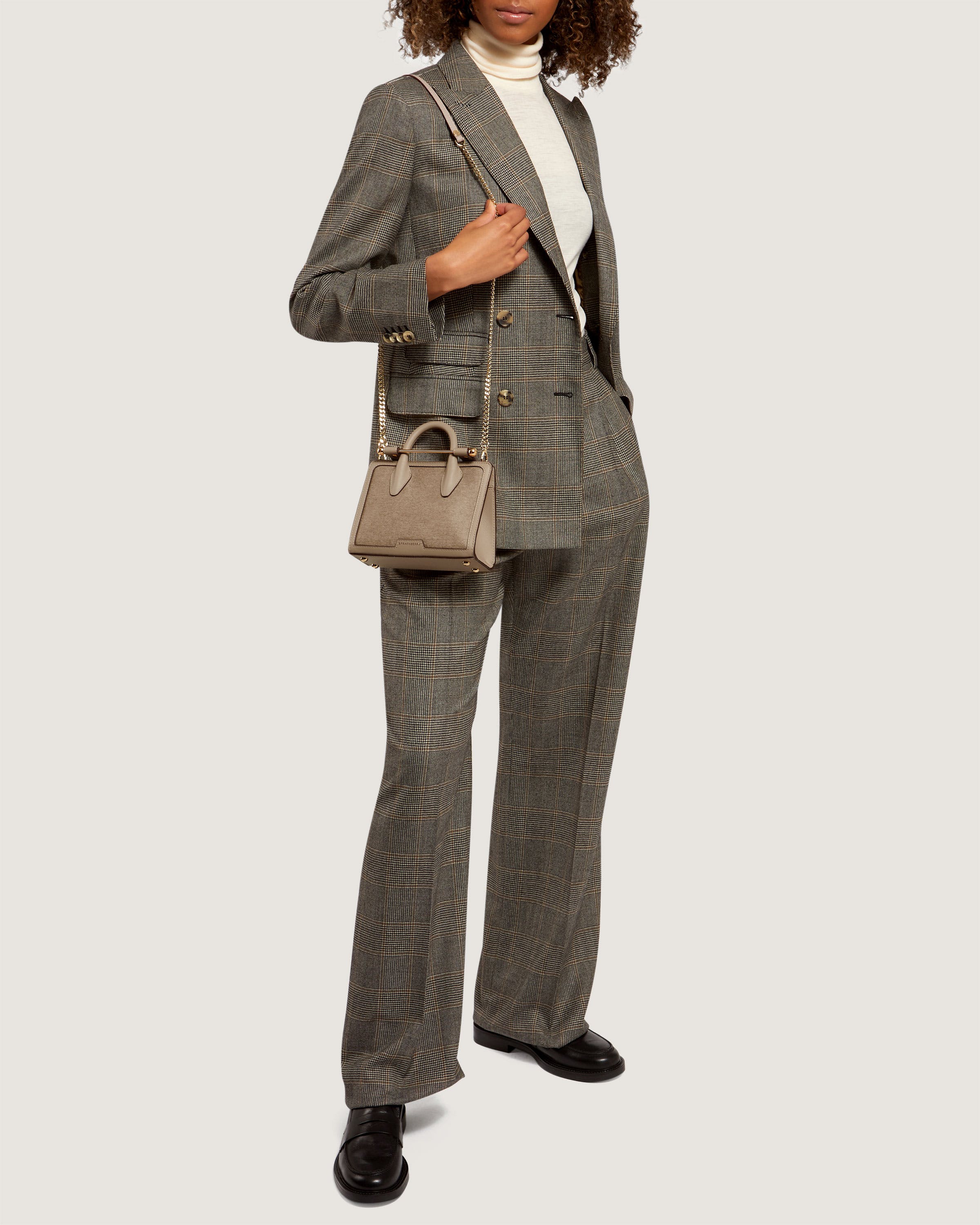 A woman in a suit holding a purse