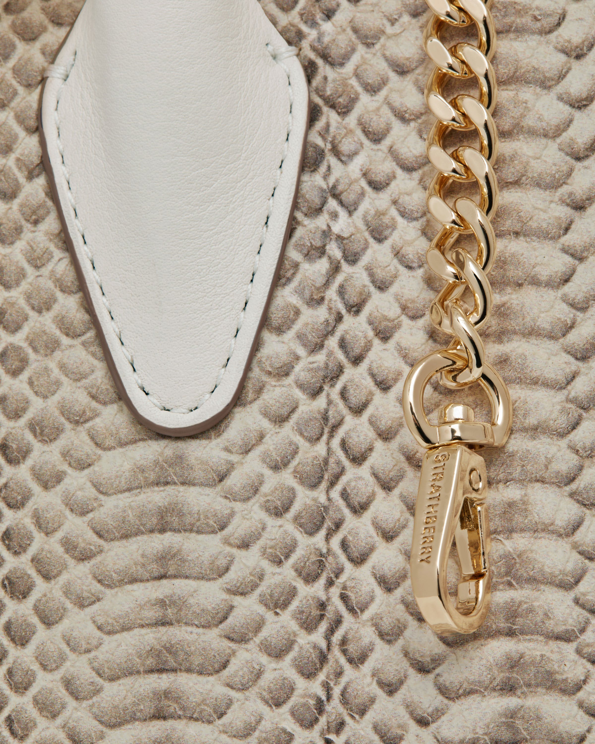 A white purse with a gold chain hanging from it