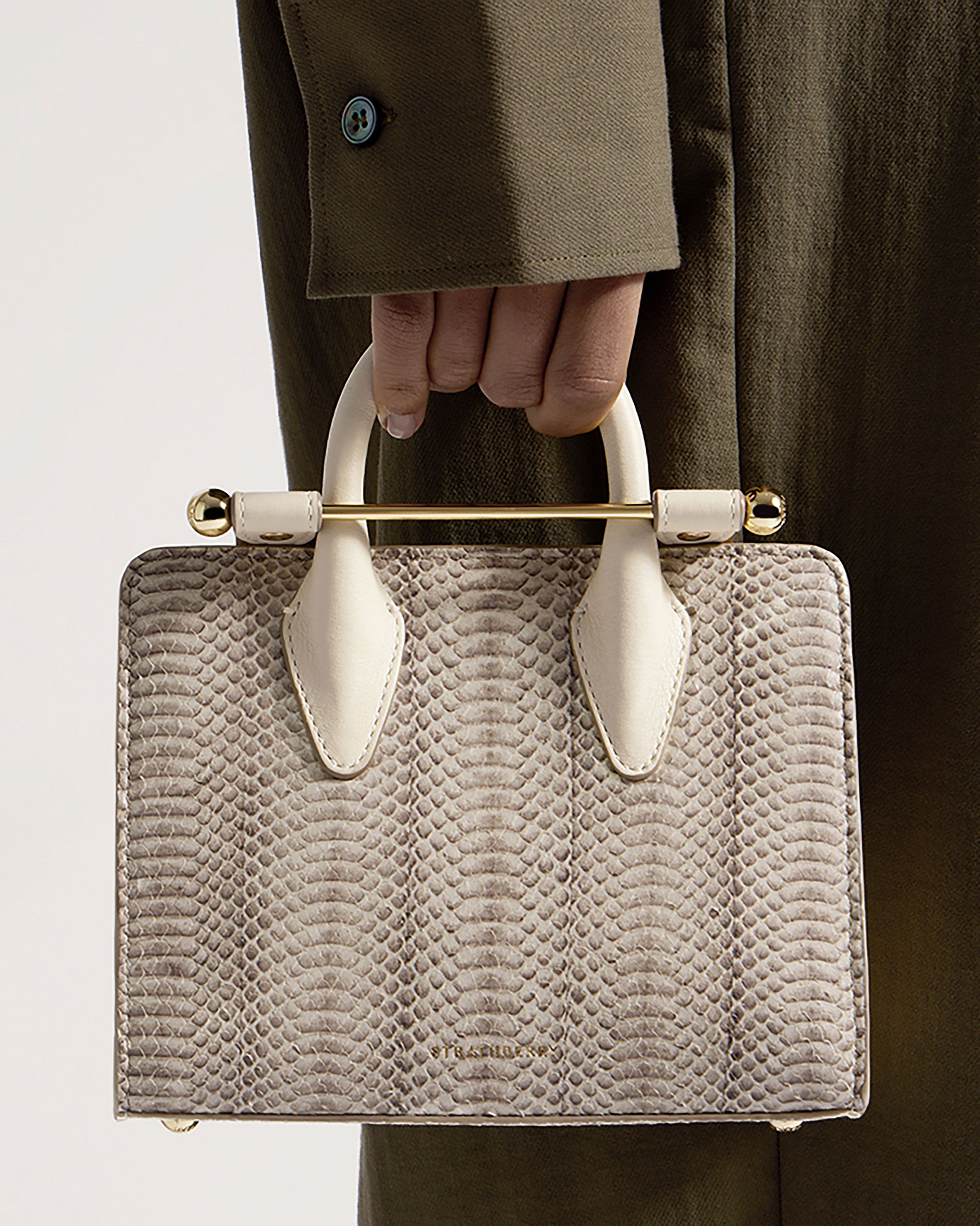 A person holding a white snake skin purse