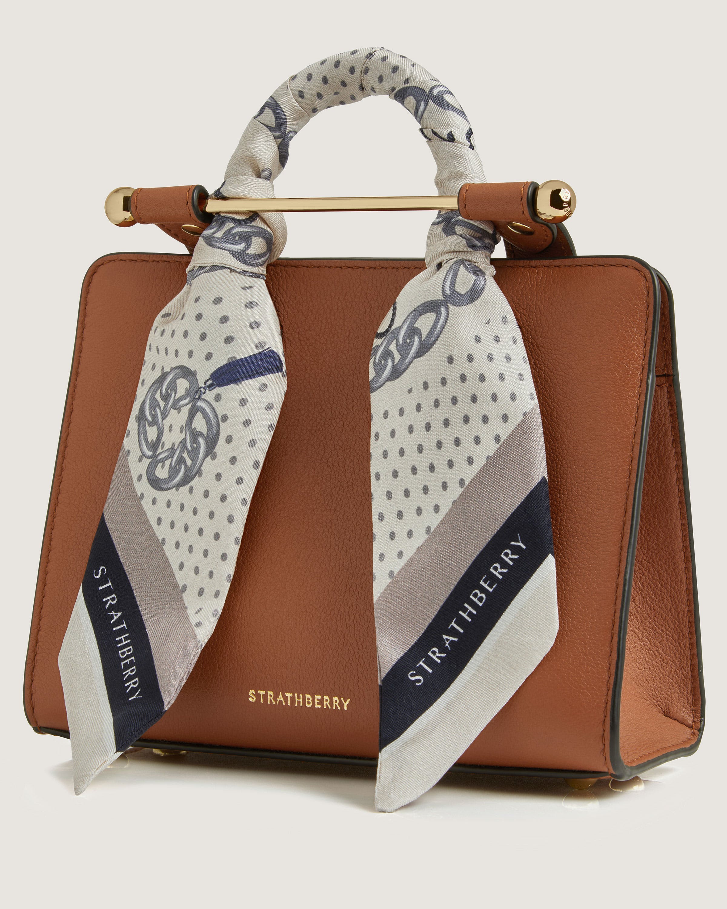 A brown purse with a white and blue scarf on top of it