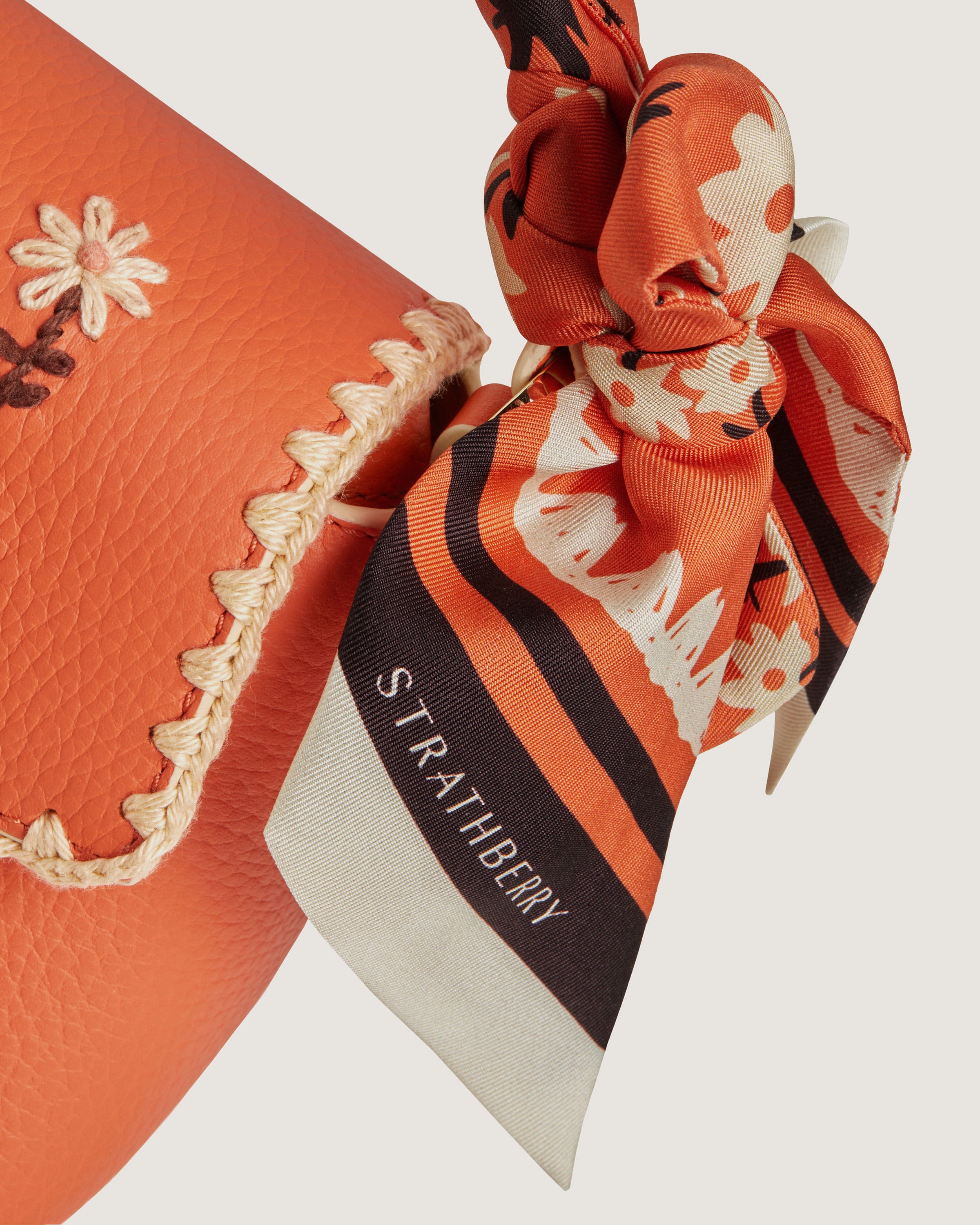 An orange purse with a bow on top of it