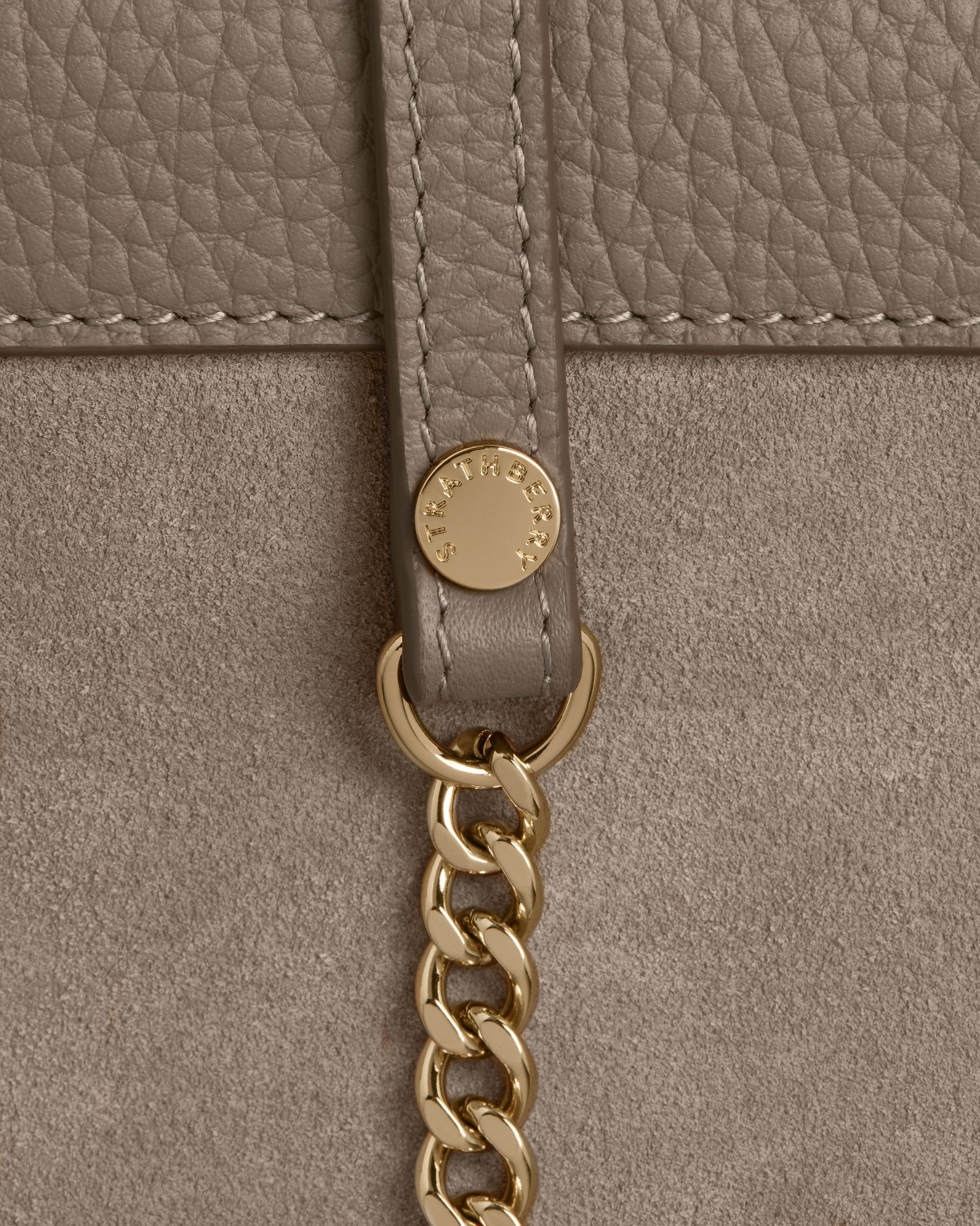 A beige purse with a gold chain hanging from it