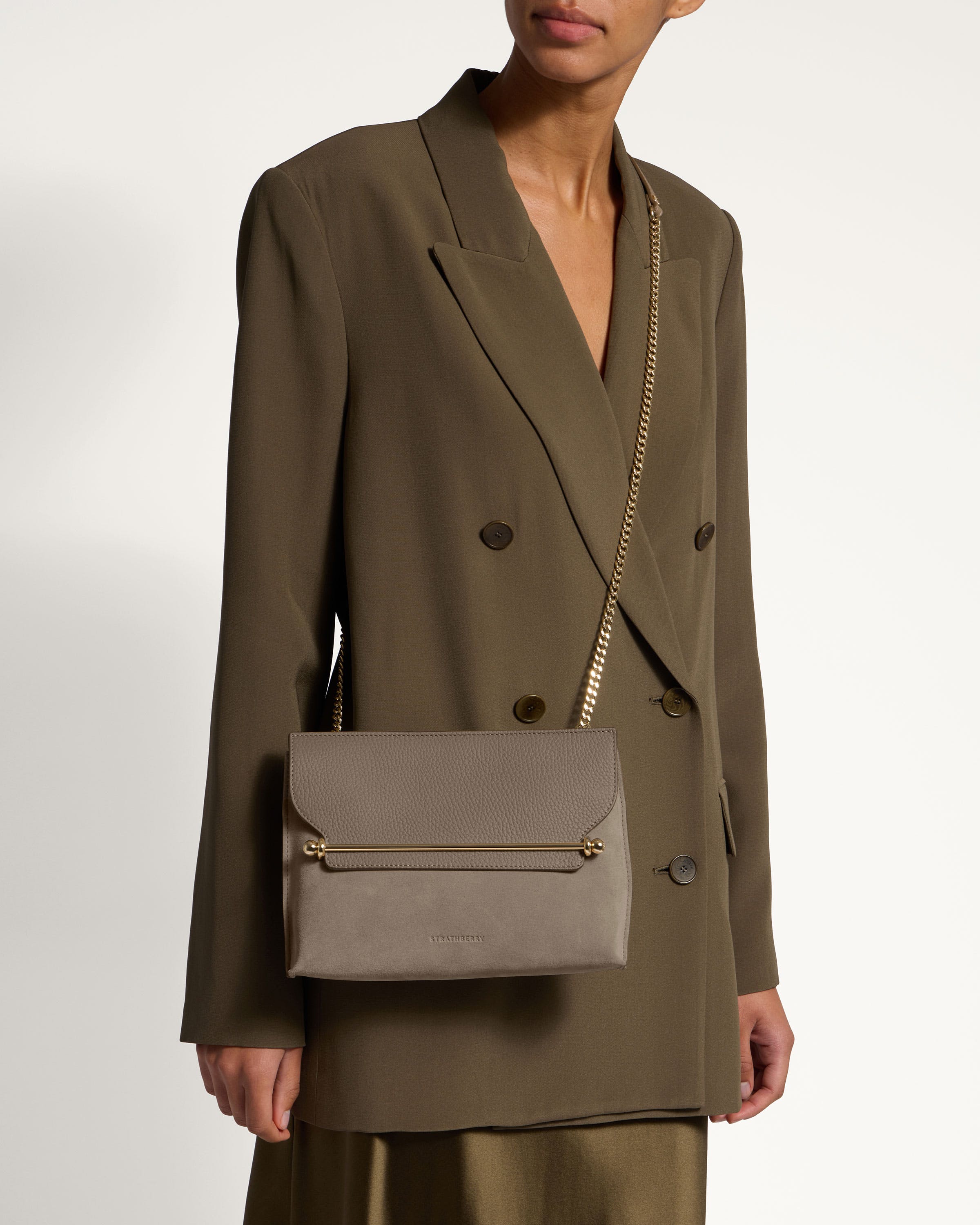 A woman in a brown suit holding a gray purse