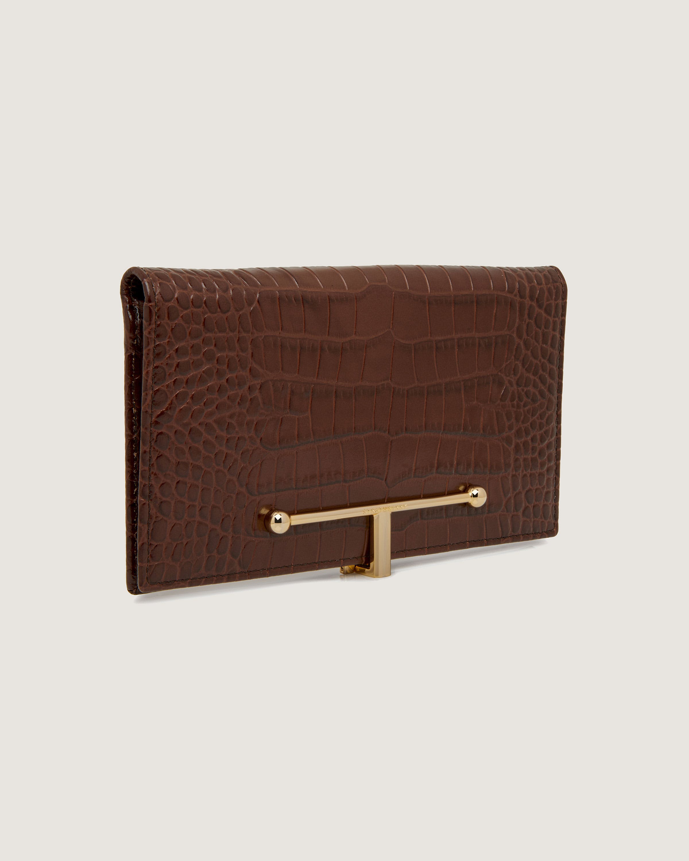 A brown alligator skin purse with a gold metal handle