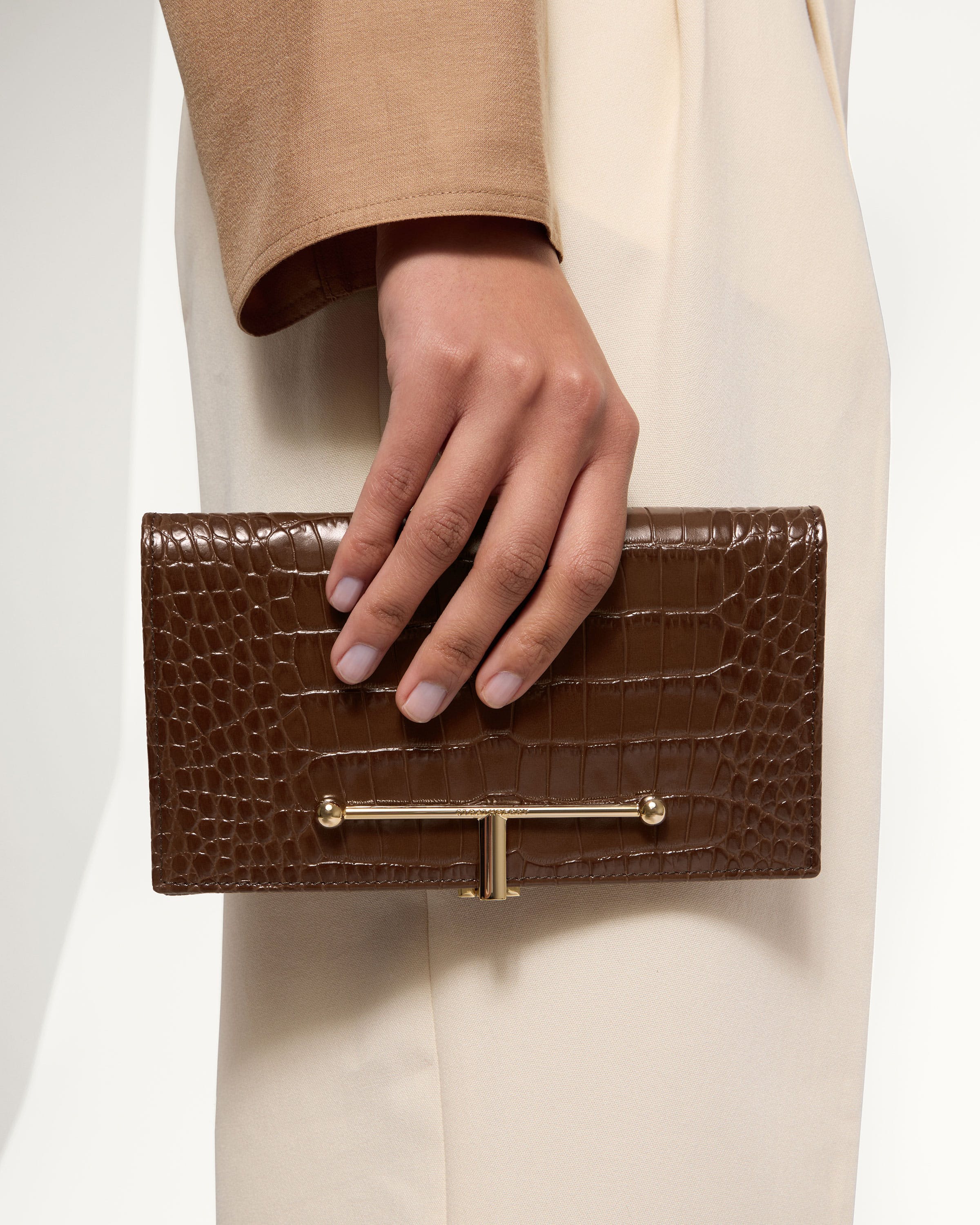 A woman's hand holding a brown purse