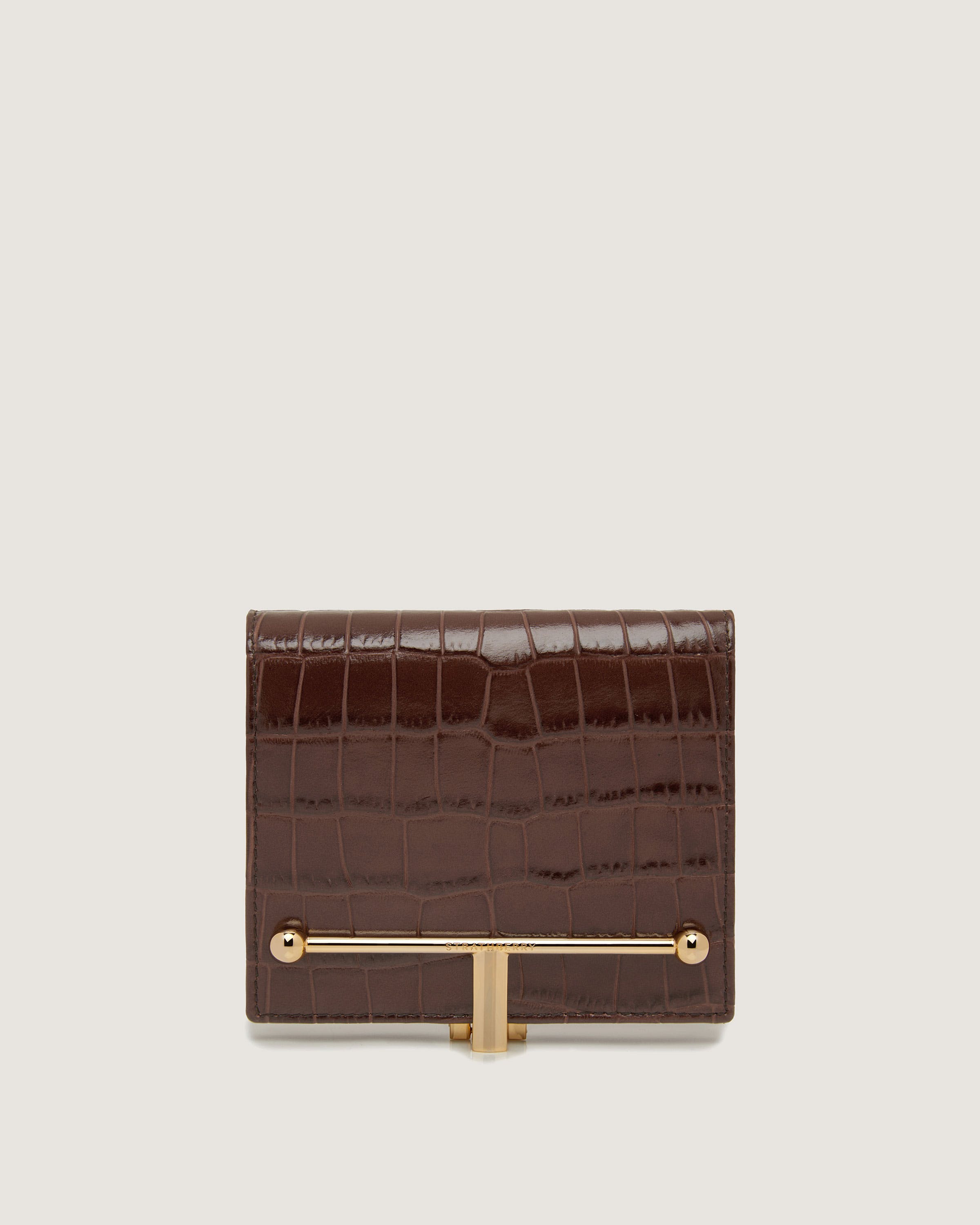 A brown alligator skin wallet with a gold bar