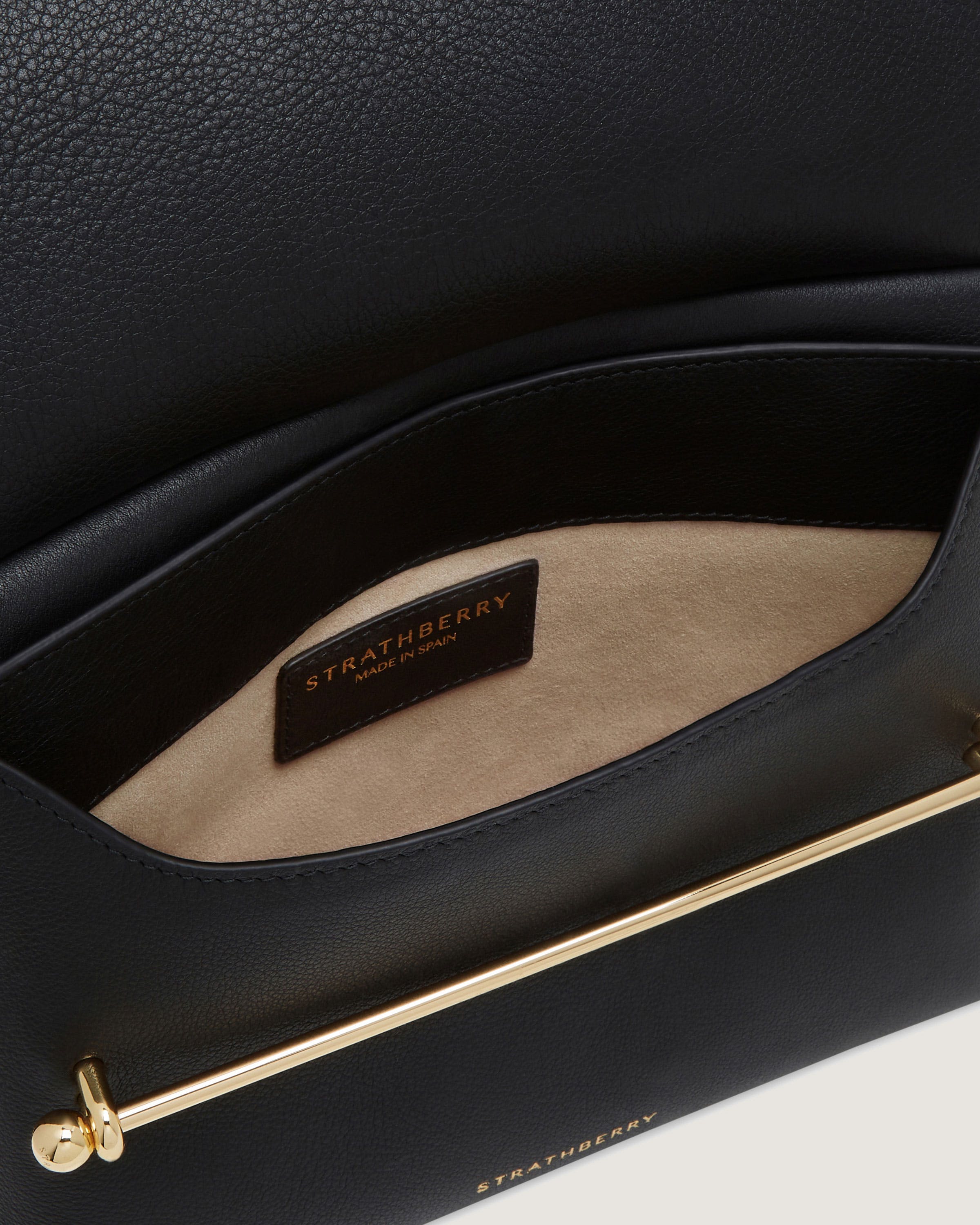 A close up of a black purse with a gold handle