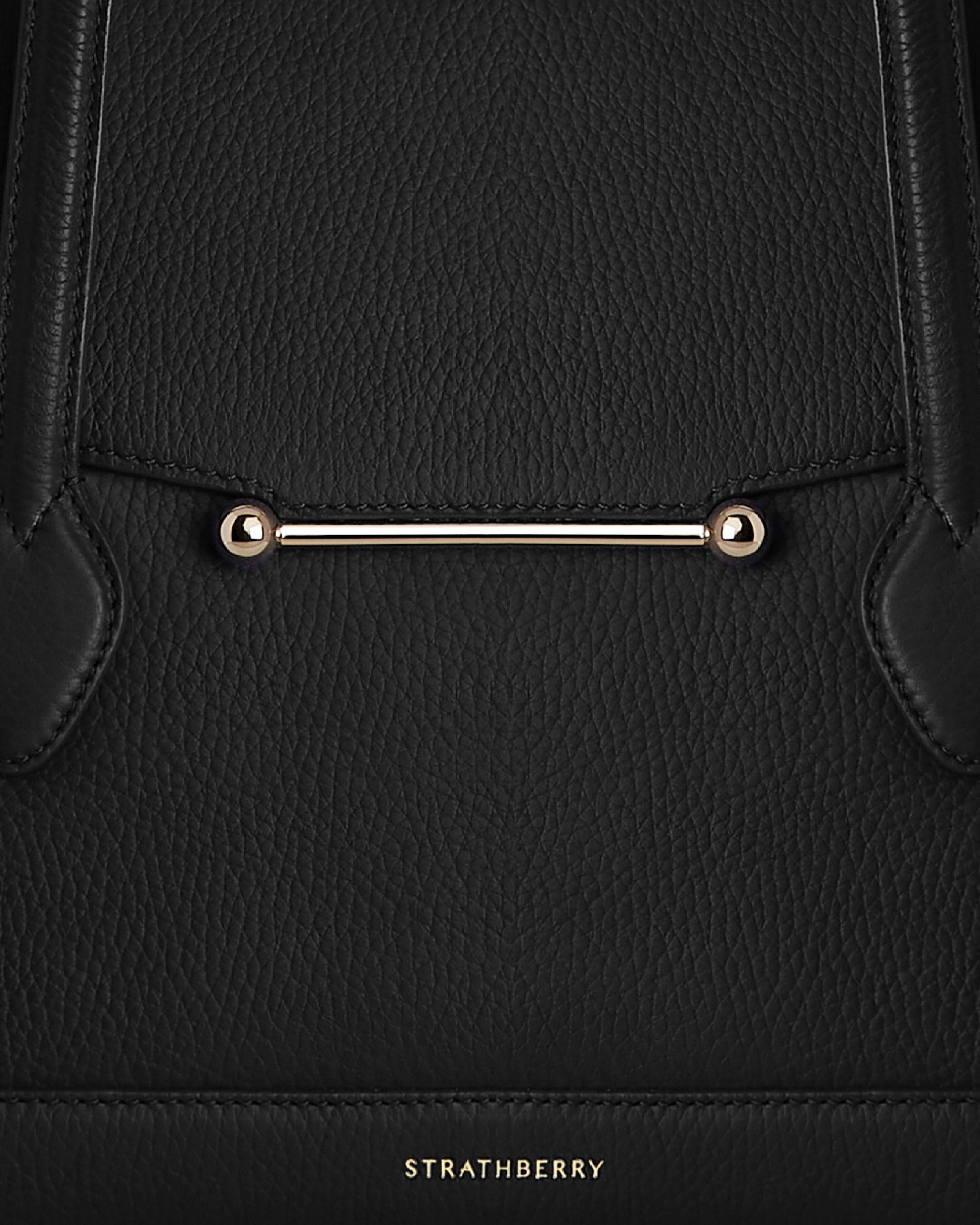 A black handbag with a gold handle