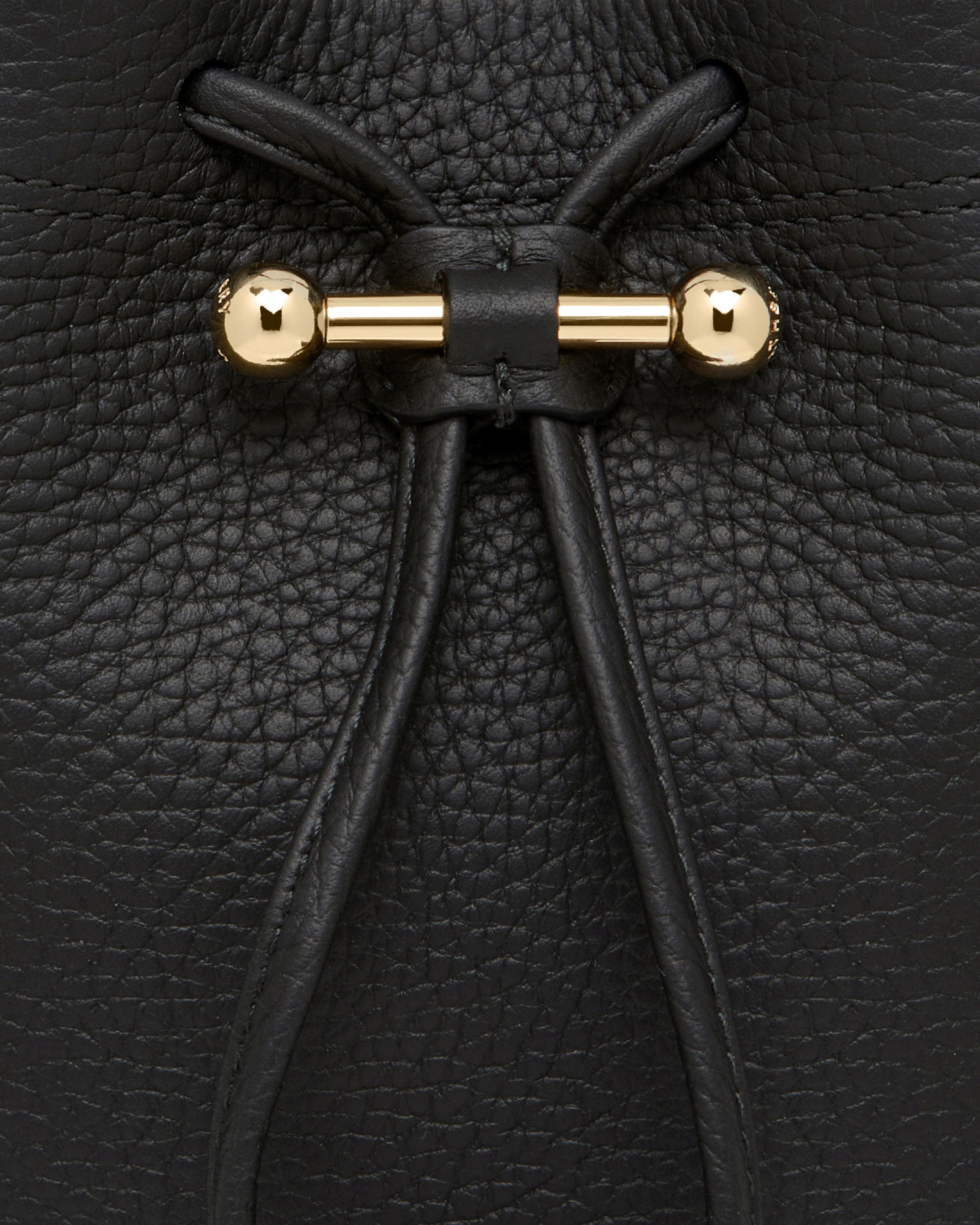 A close up of a black purse with gold handles