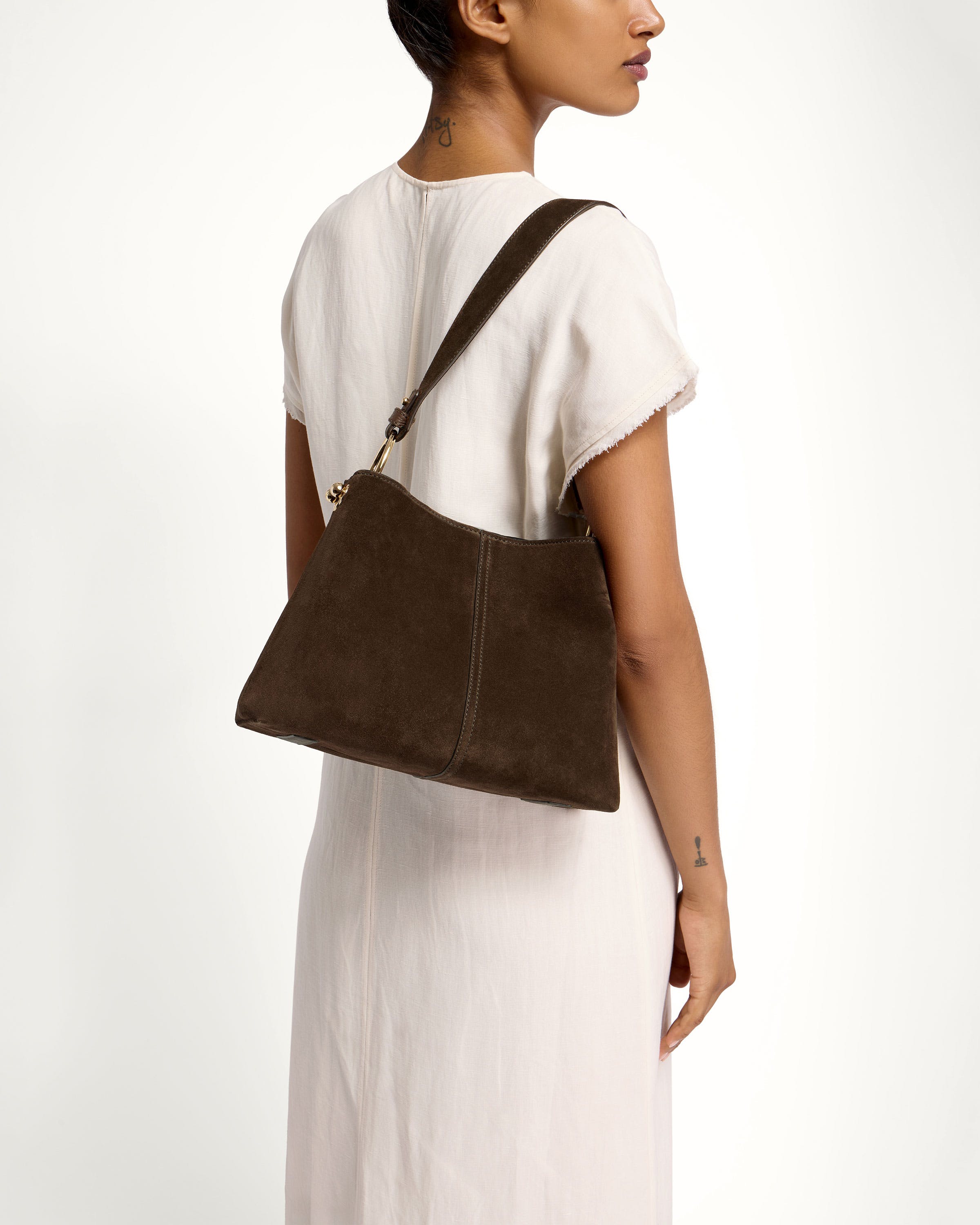 A woman in a white dress holding a brown purse