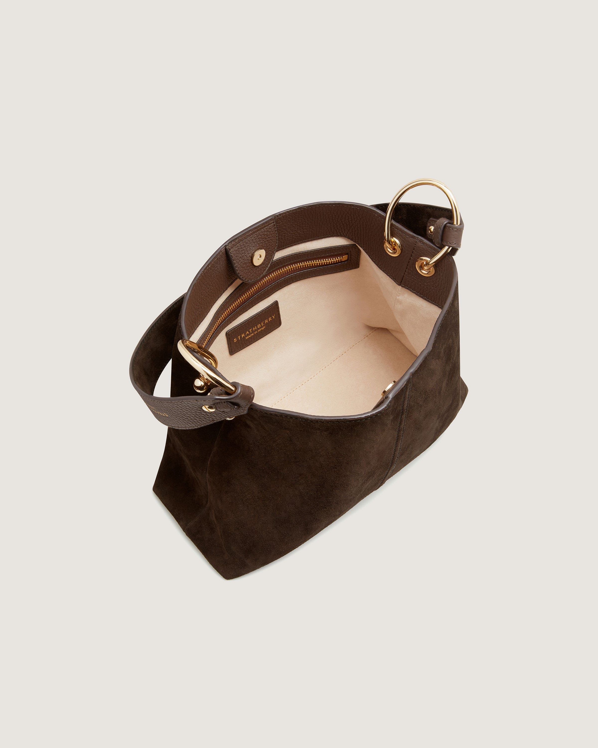 A brown suede bag with a gold handle