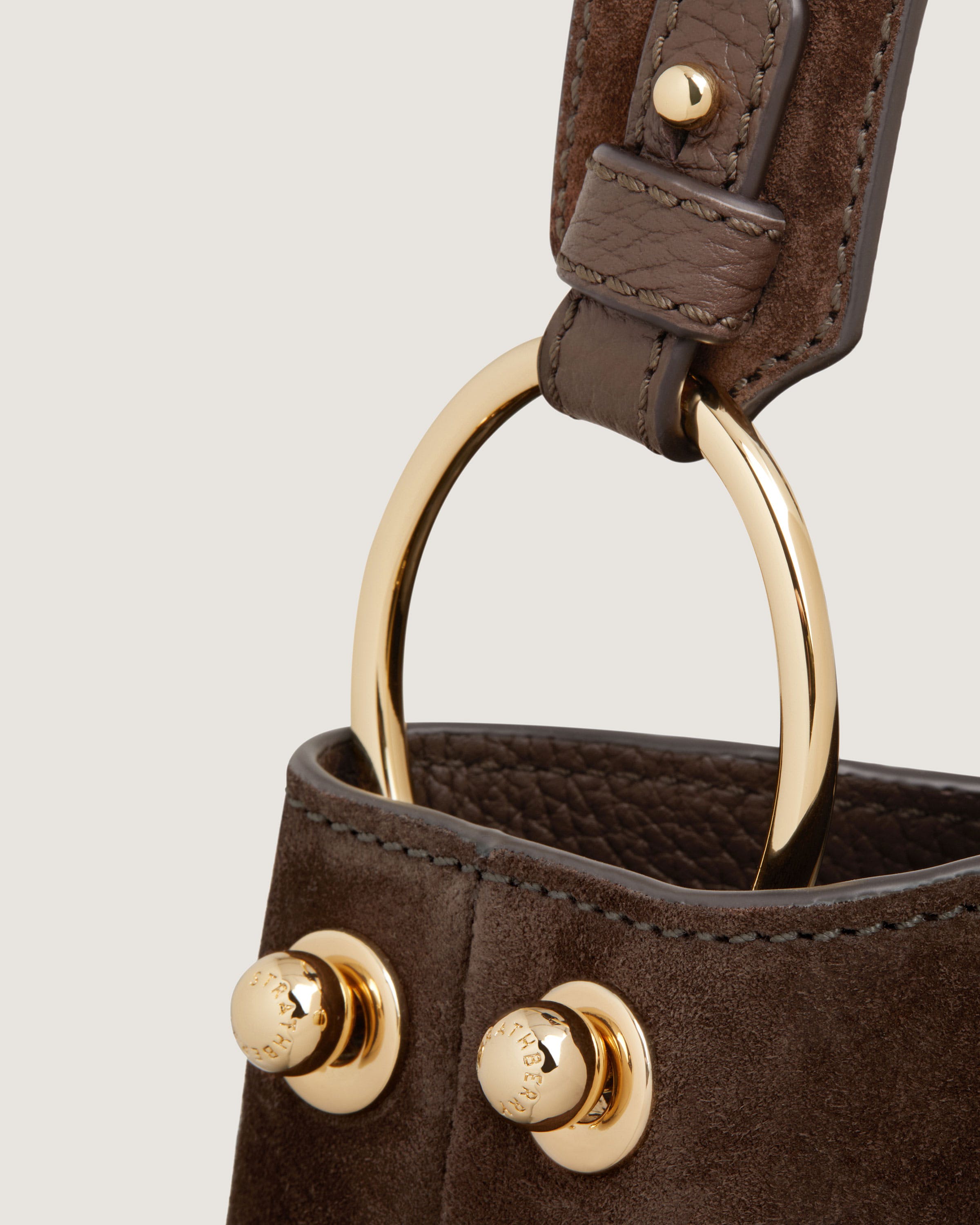 A brown purse with a gold ring handle