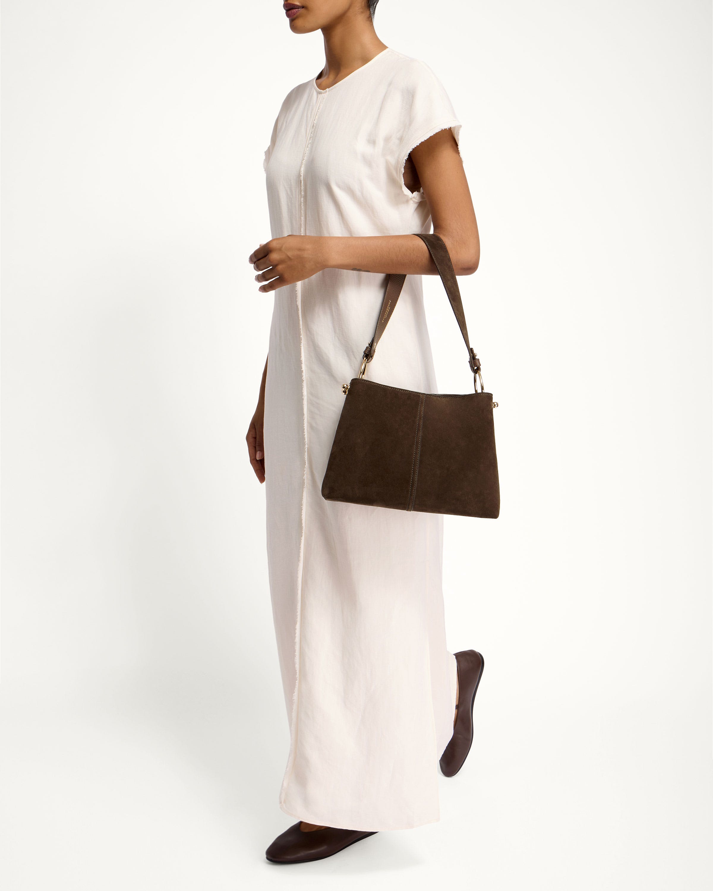 A woman in a white dress holding a brown purse