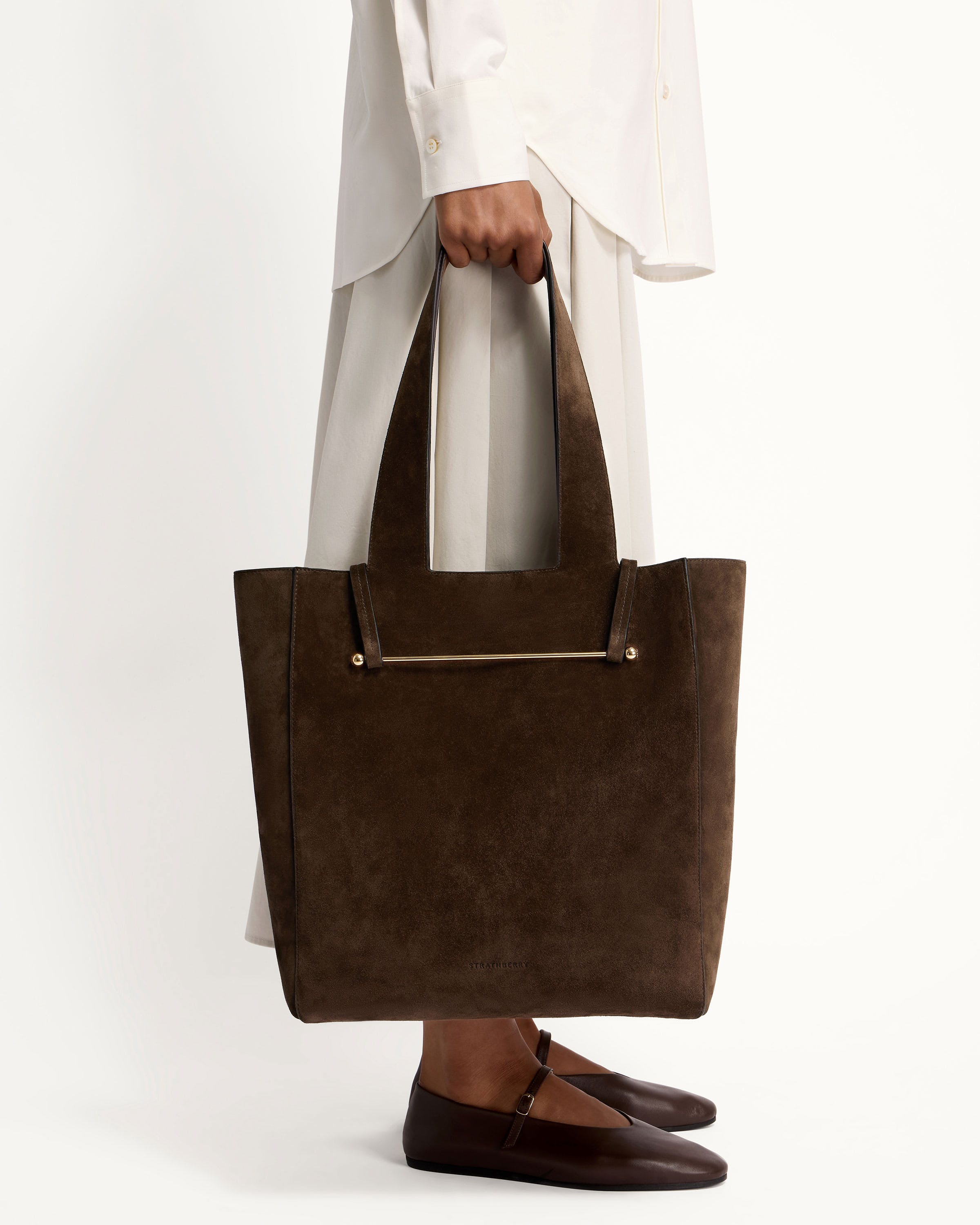 A woman holding a brown suede tote bag