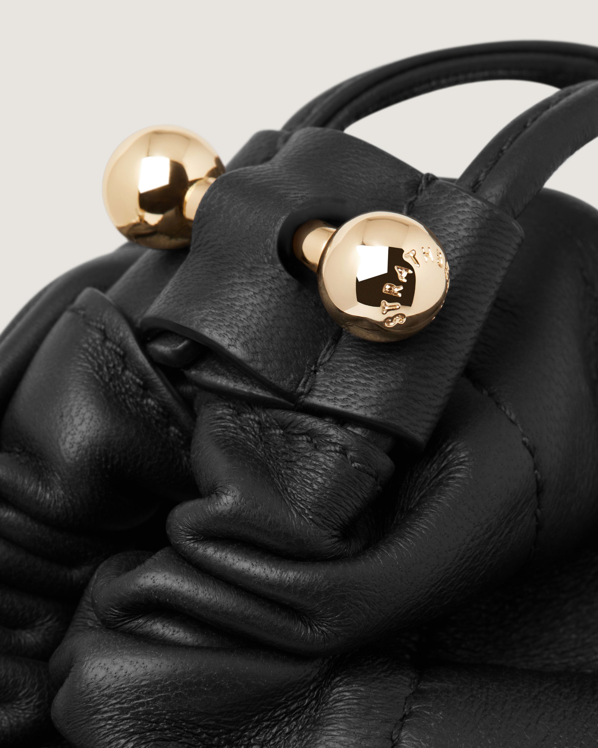 A black handbag with gold buttons on it