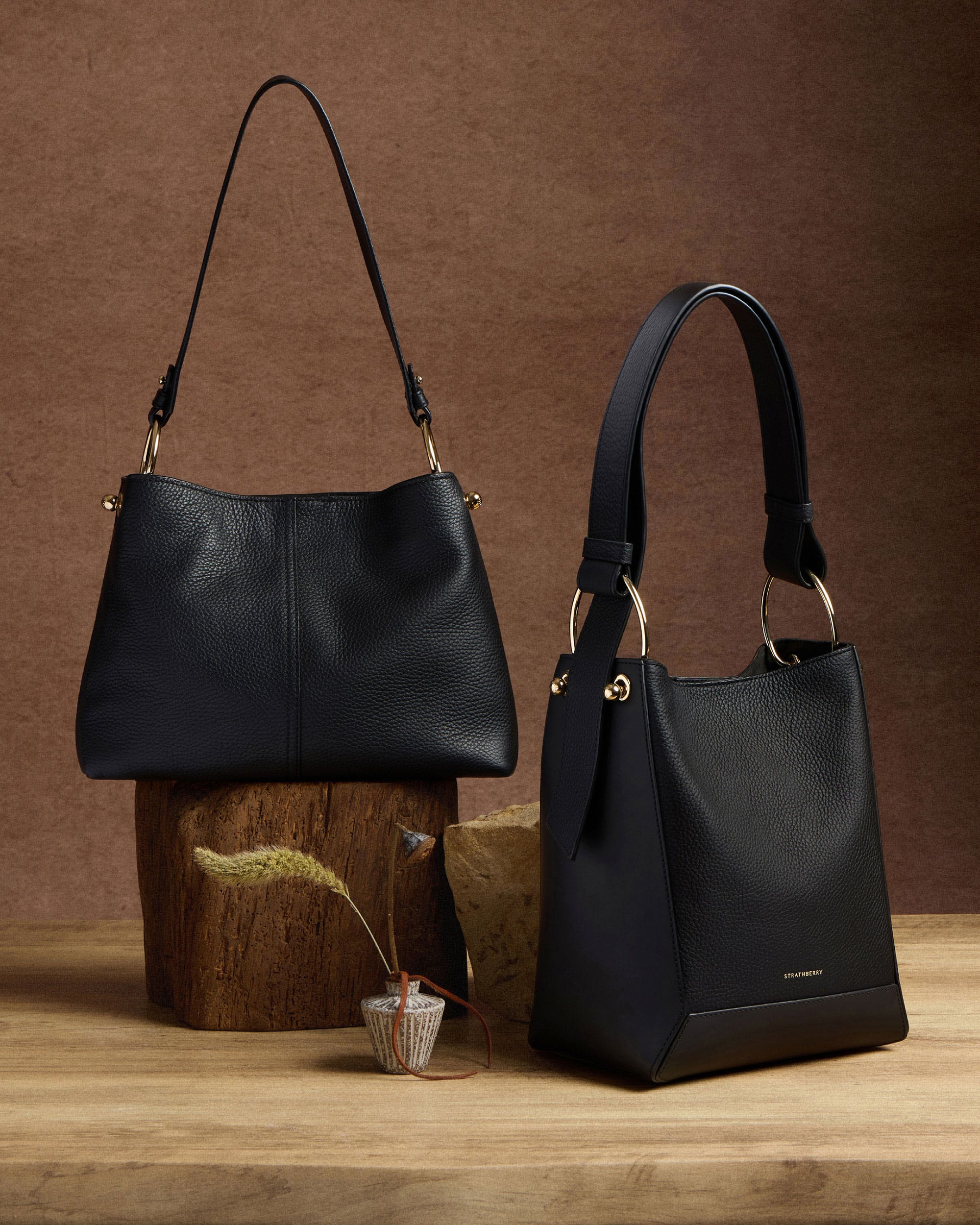 Two black purses sitting on top of a wooden stump