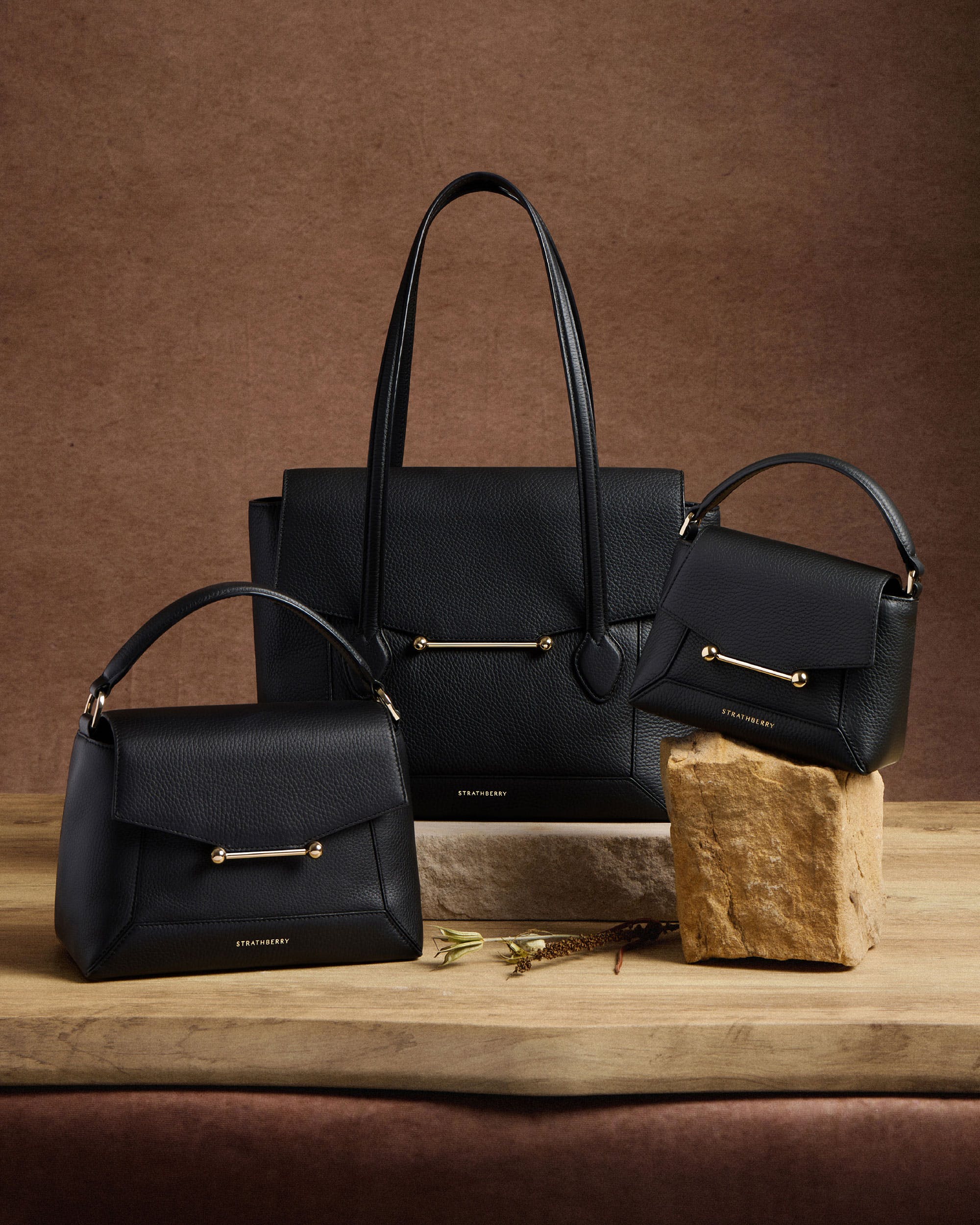 Three black purses sitting on top of a wooden table