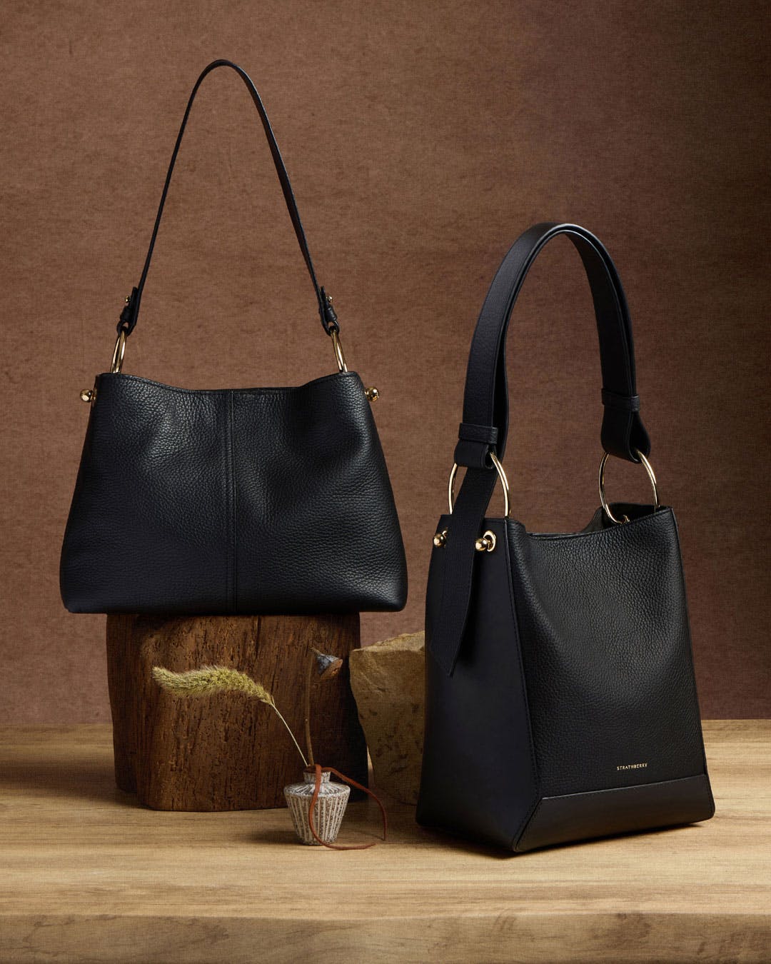 A pair of black purses sitting on top of a wooden stump