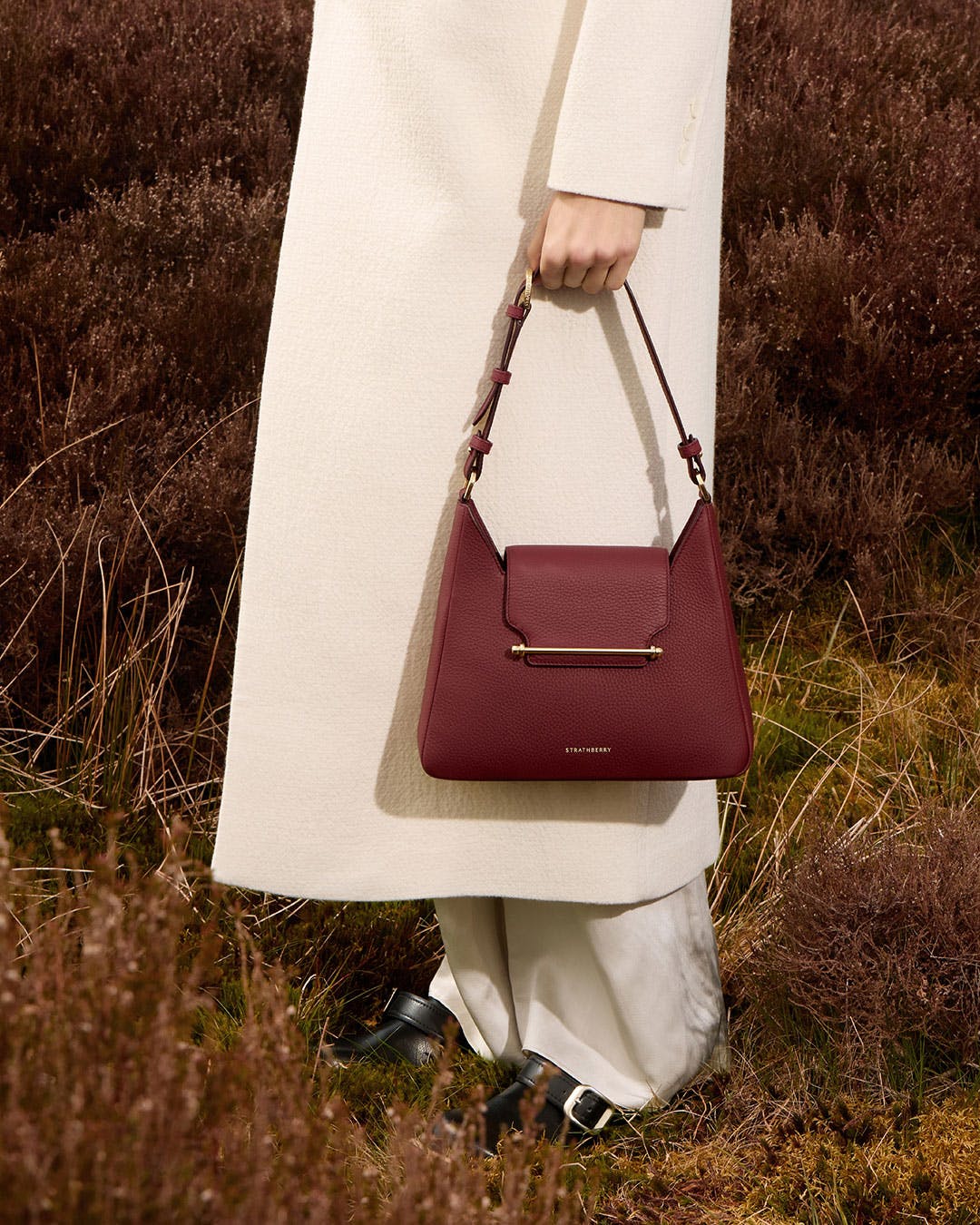 A woman in a white coat carrying a red handbag