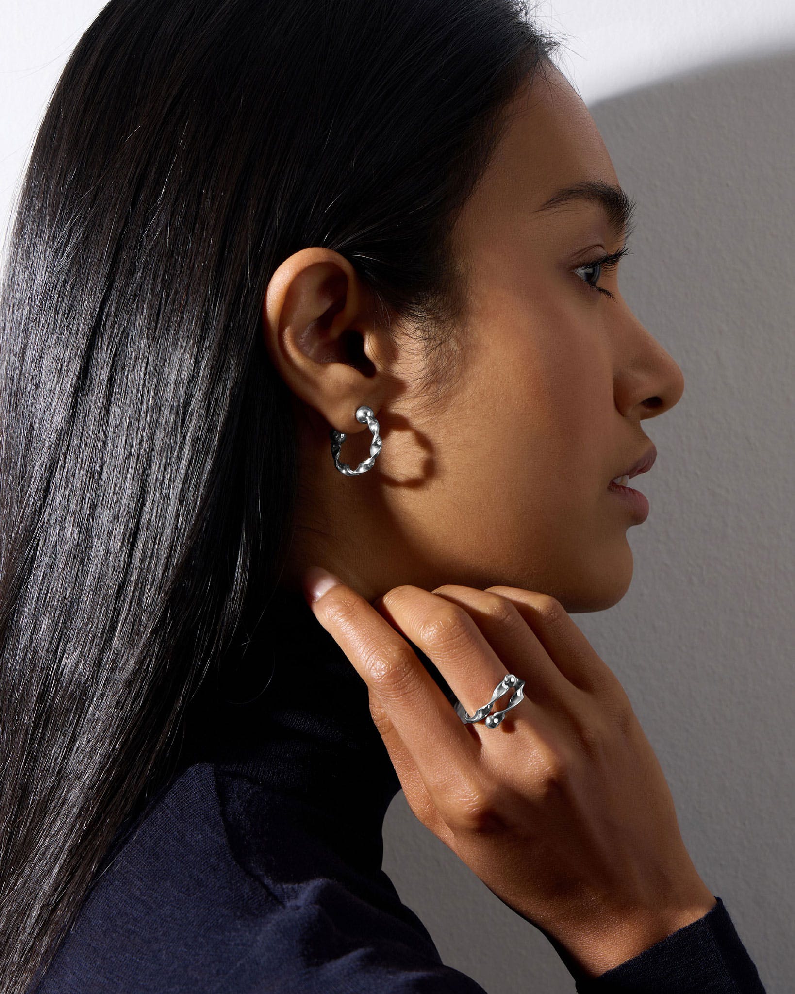 A woman wearing a pair of silver earrings