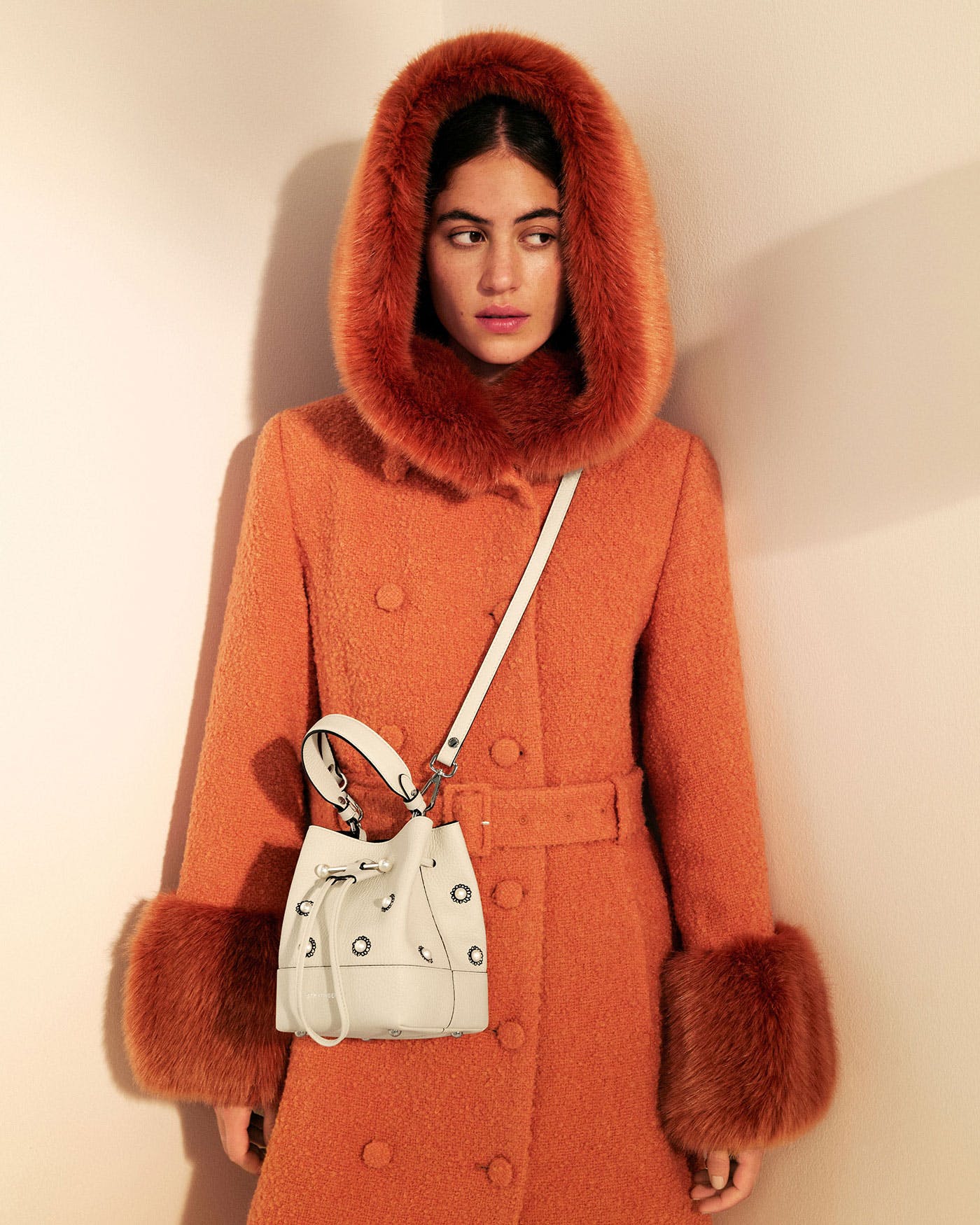 A woman in an orange coat with a white purse