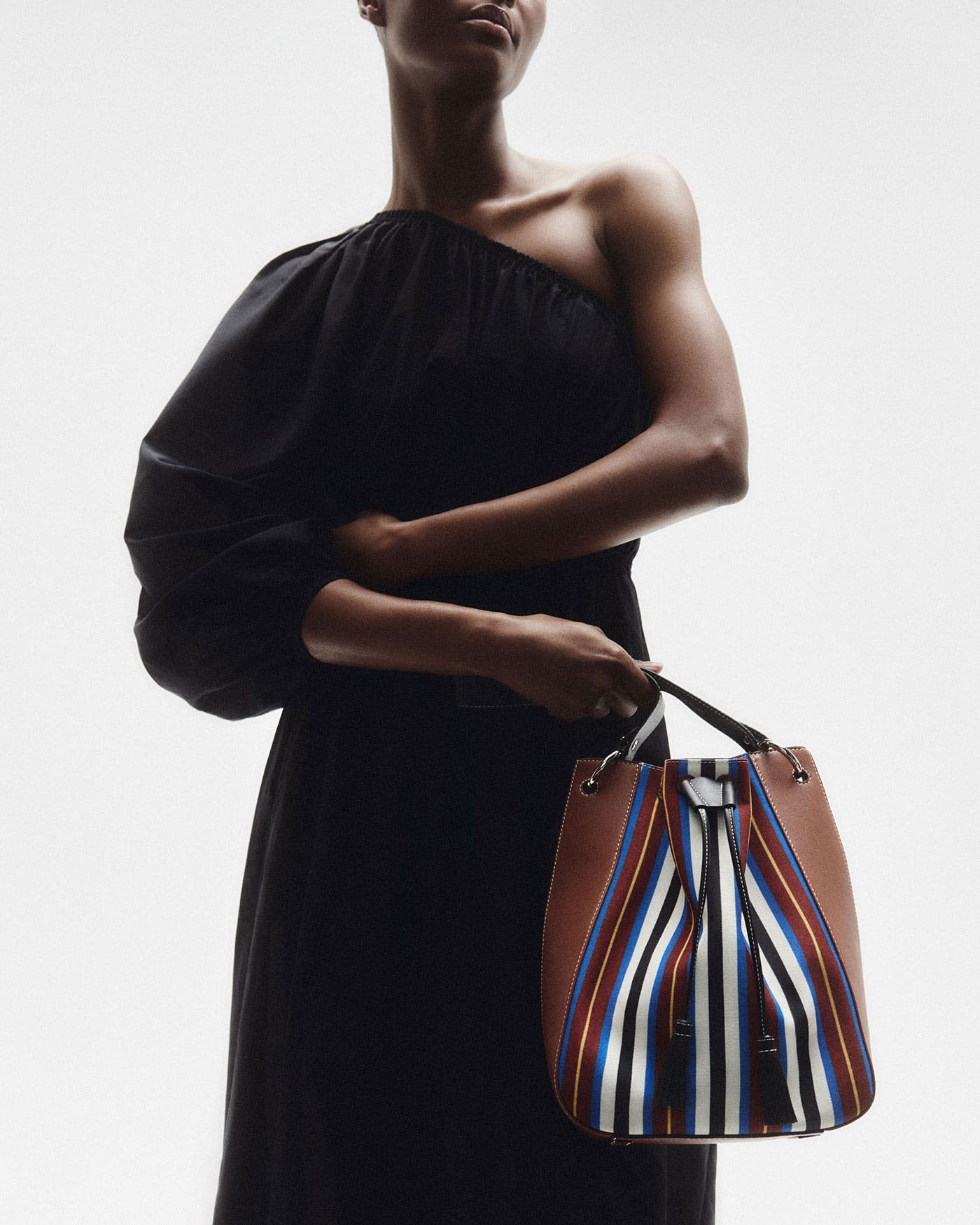 A woman in a black dress holding a striped purse