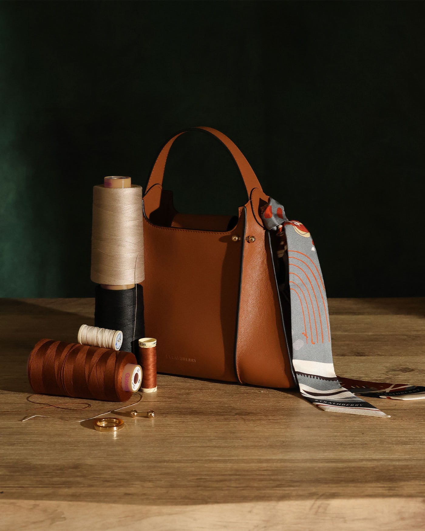 A brown bag sitting on top of a wooden table next to a spool of