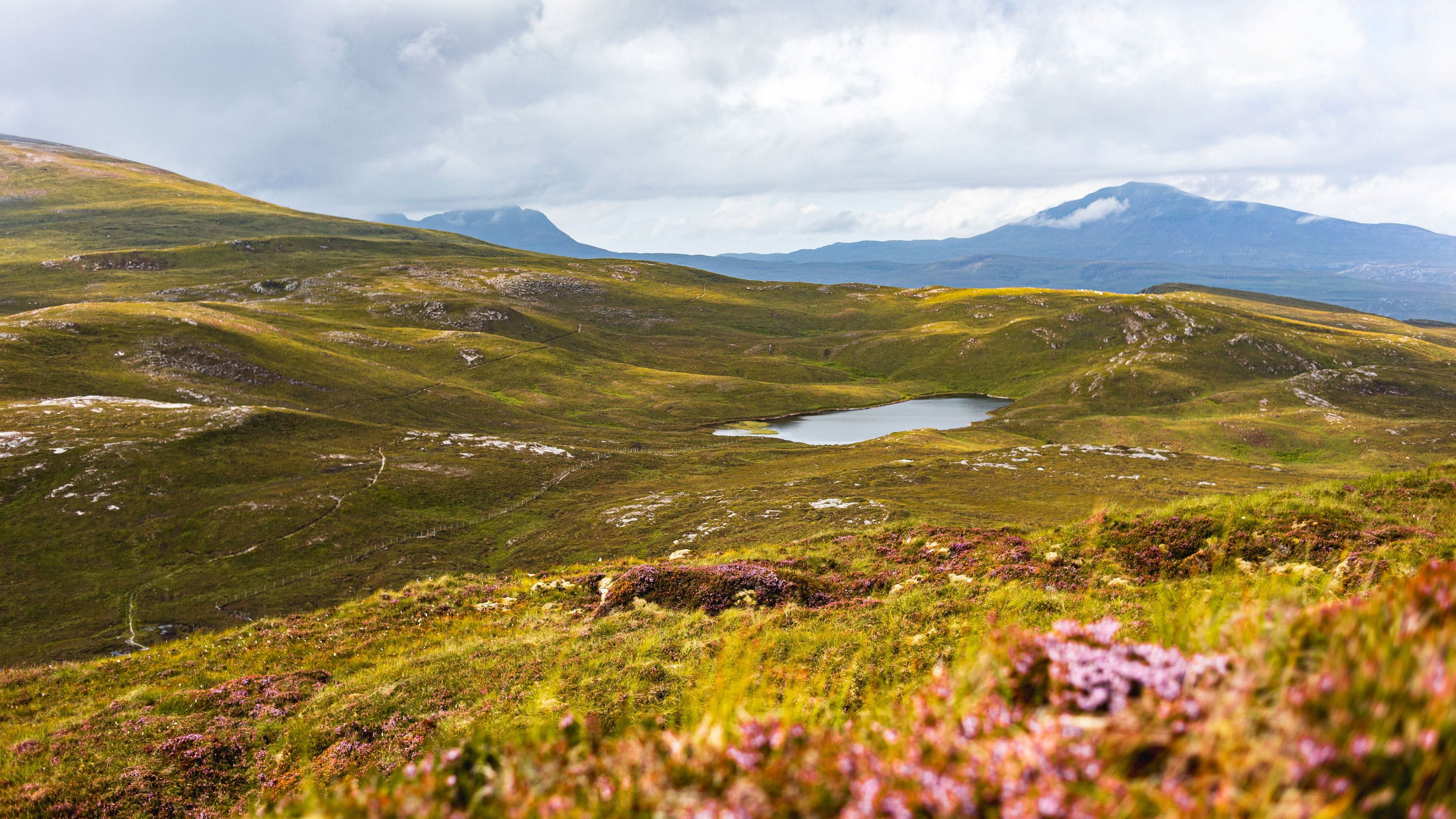 A grassy hill with a lake in the middle of it