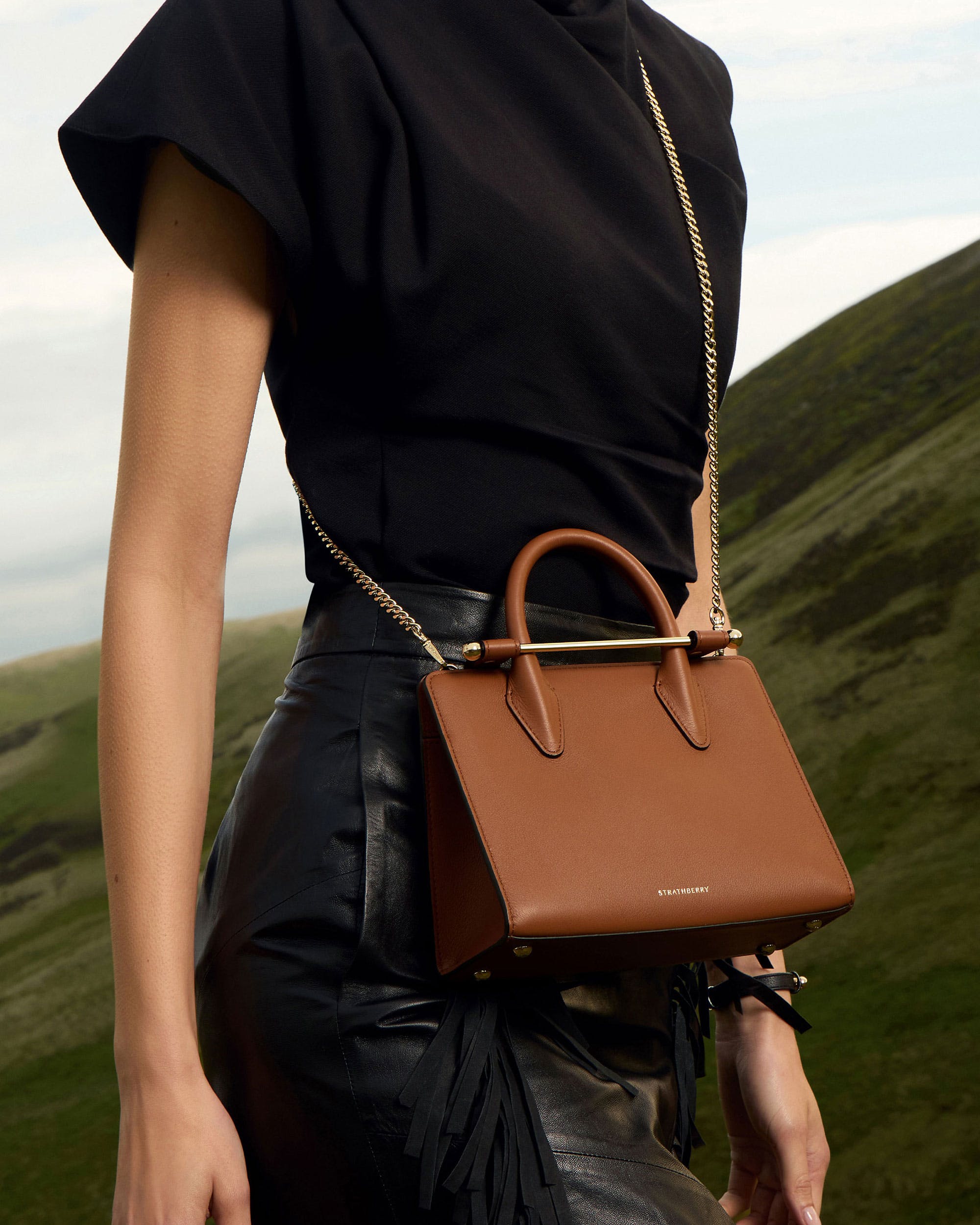 A woman holding a brown purse in her hand