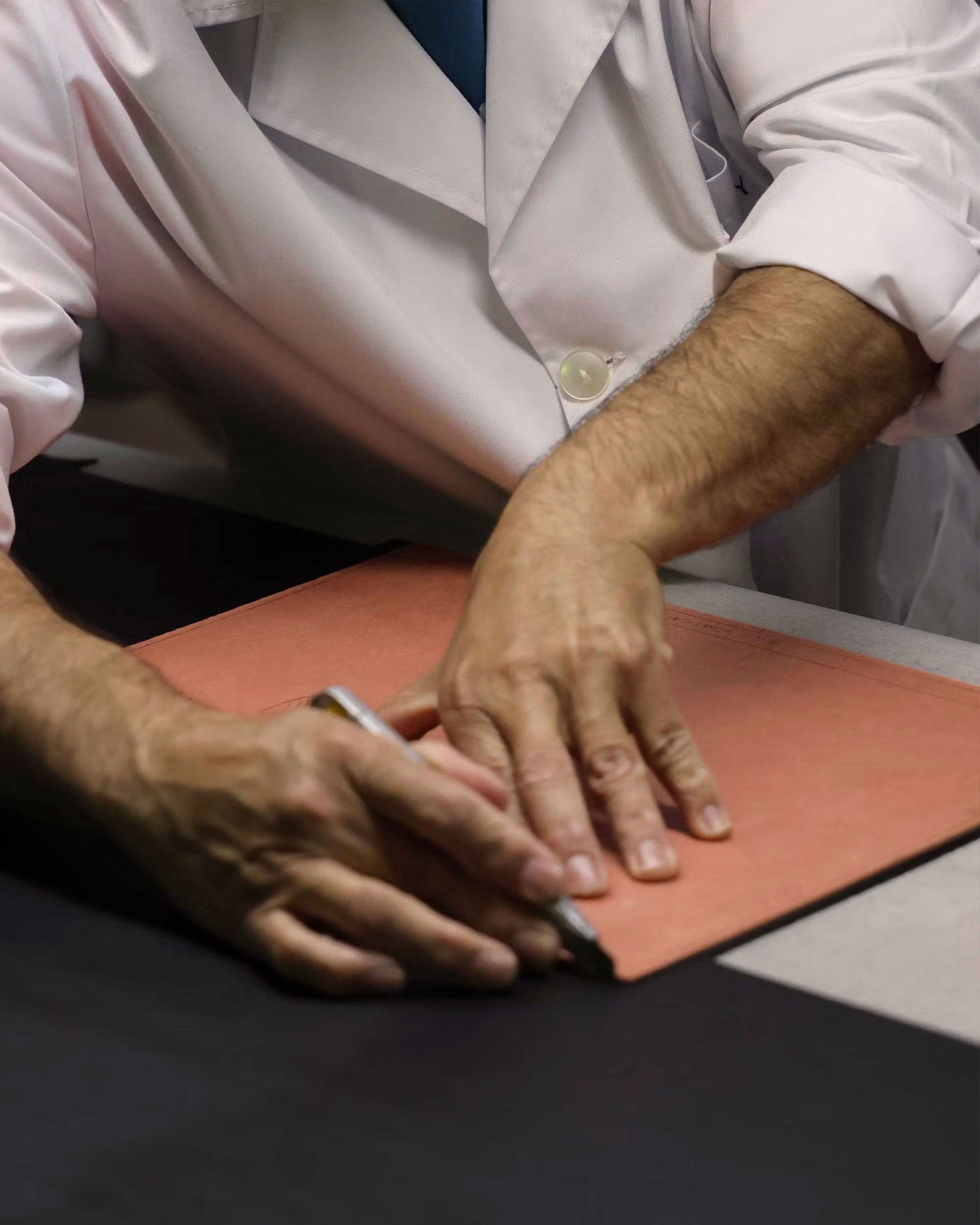 A man in a white shirt and tie is cutting a piece of paper