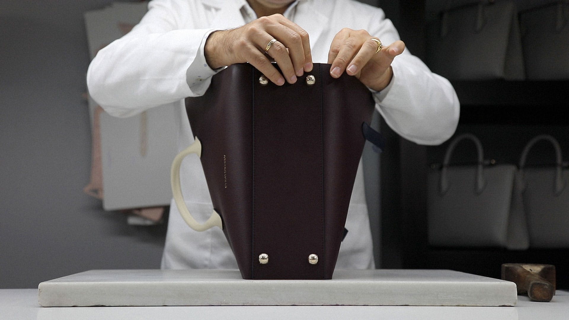 A woman in a white shirt is holding a brown purse