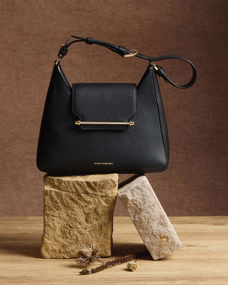 A black purse sitting on top of a wooden block