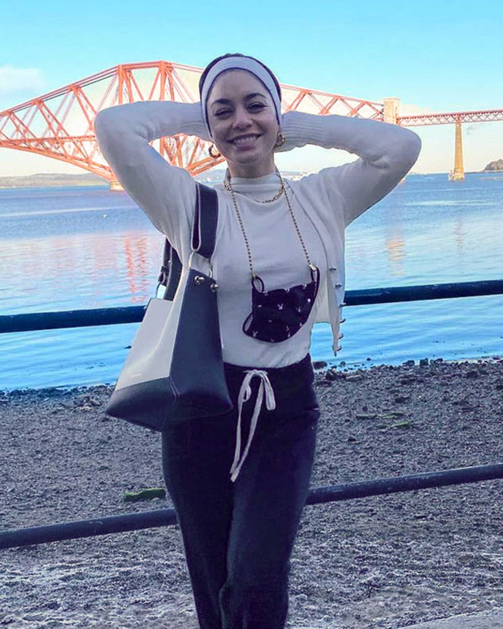 A woman standing on a beach holding a purse