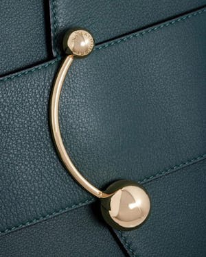 A close up of a handle on a green purse