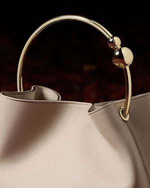 A white purse with a gold handle on a black background