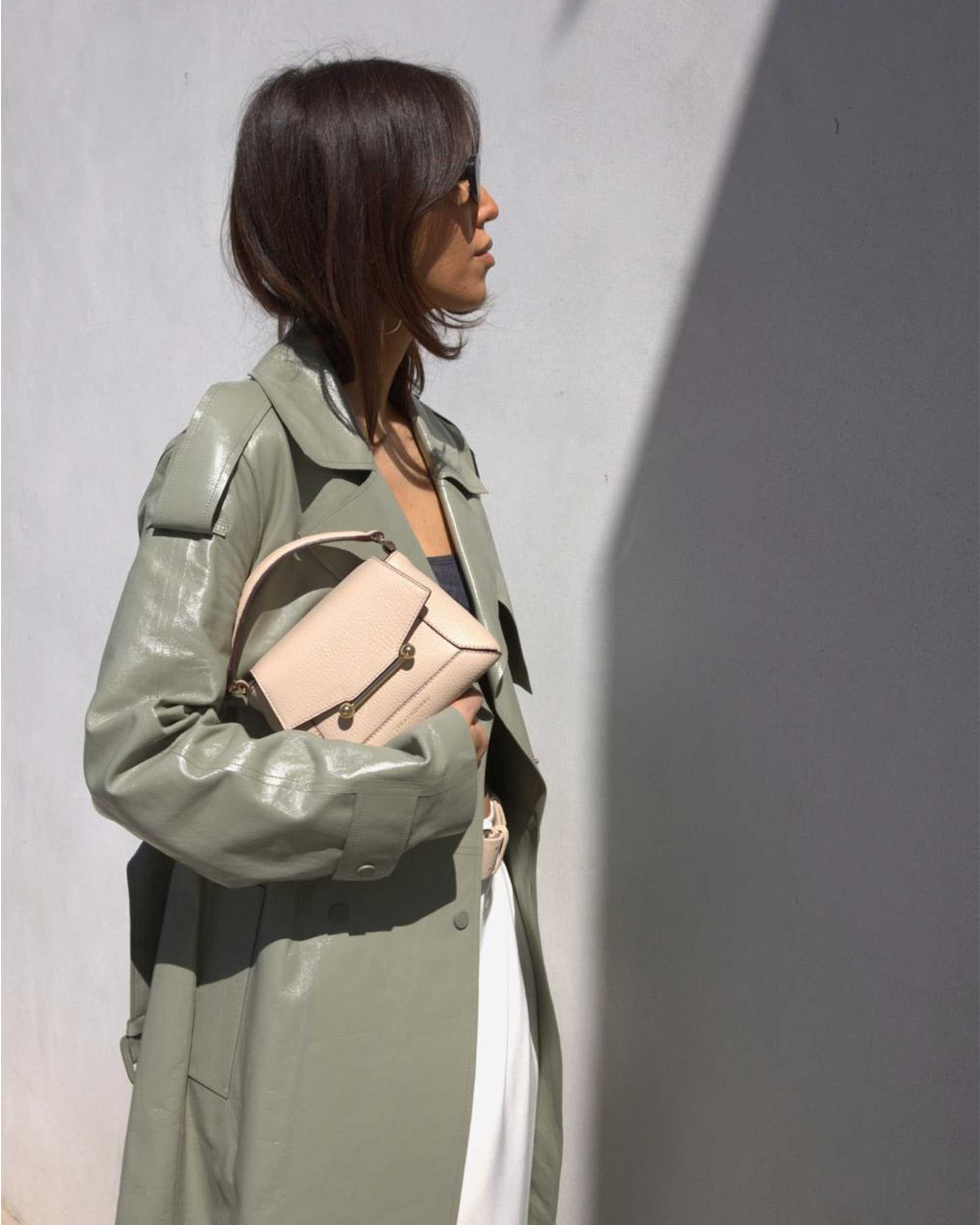 A woman in a trench coat holding a pink purse