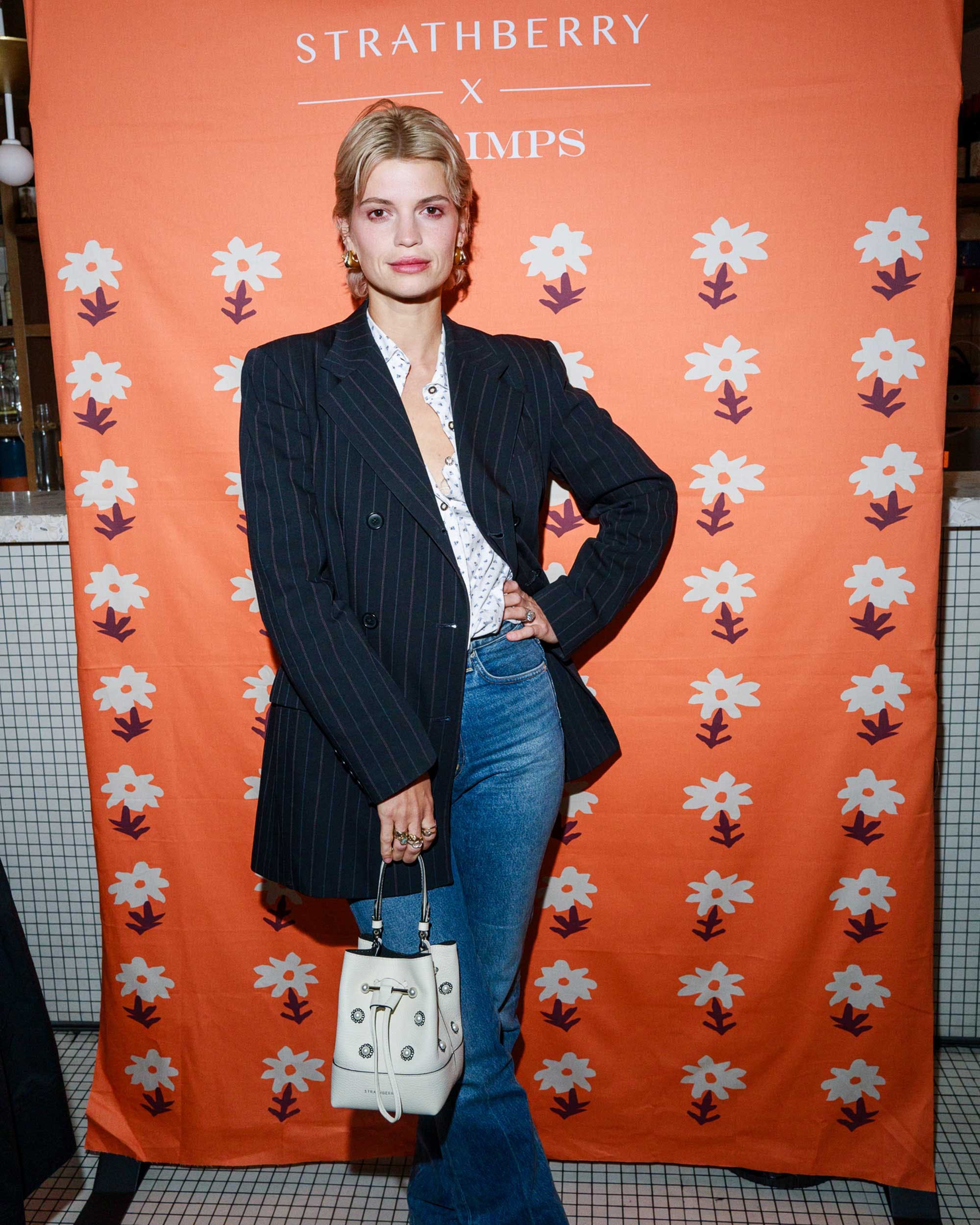 A woman standing in front of a wall holding a purse