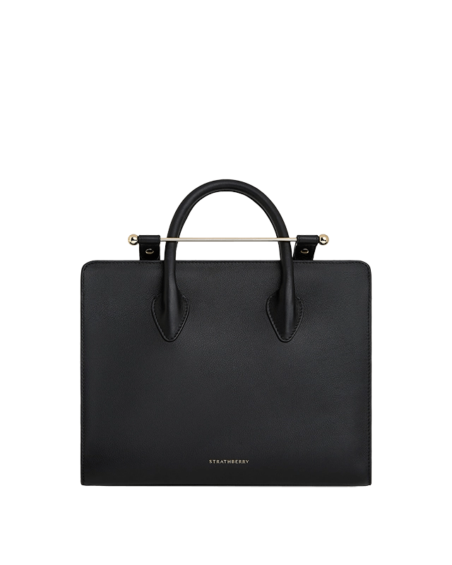 A black handbag with a handle on a green background