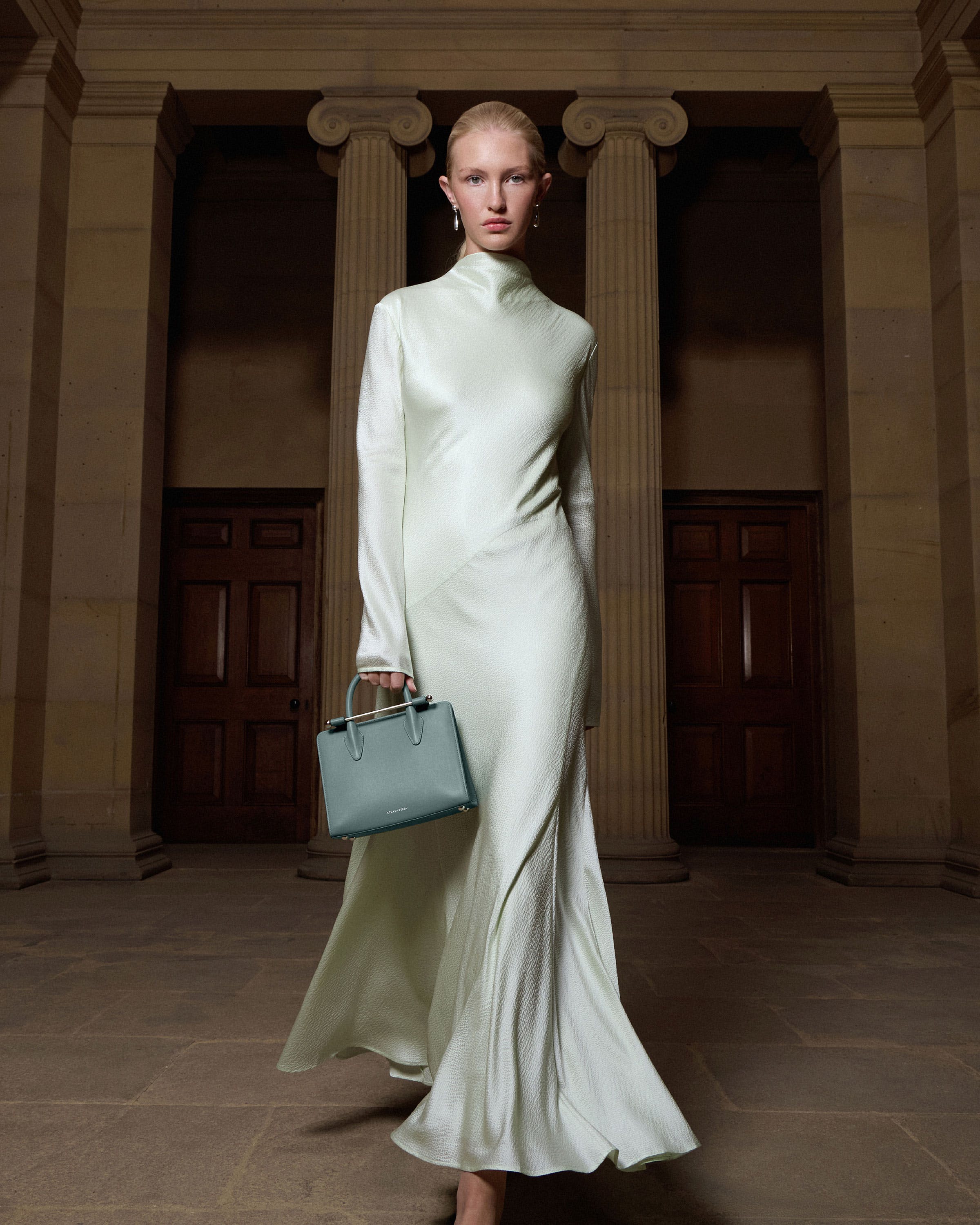 A woman in a white dress holding a blue purse