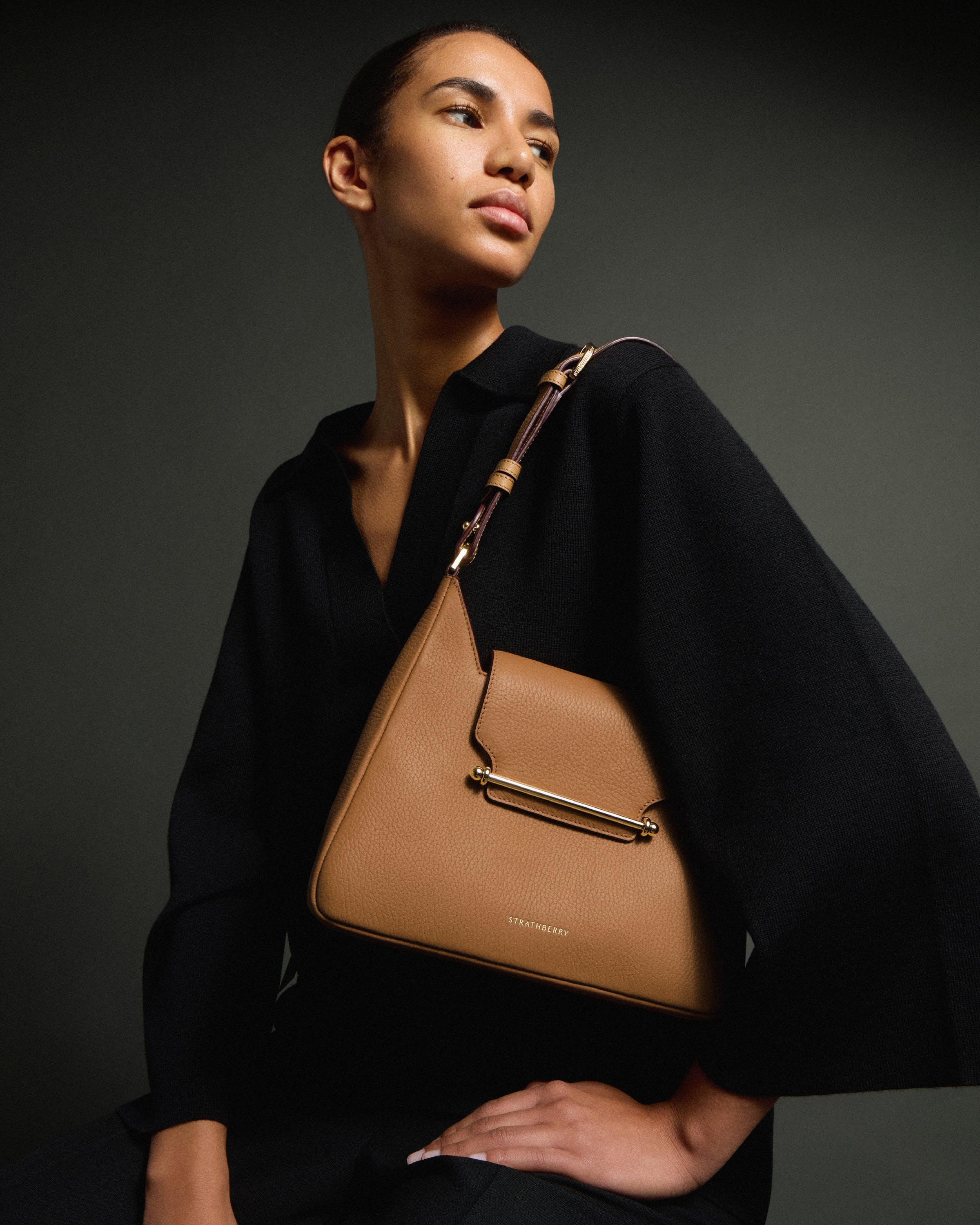 A woman is holding a brown purse