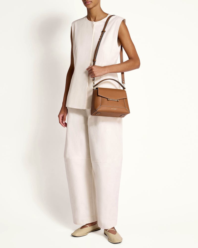 A woman in white holding a brown purse