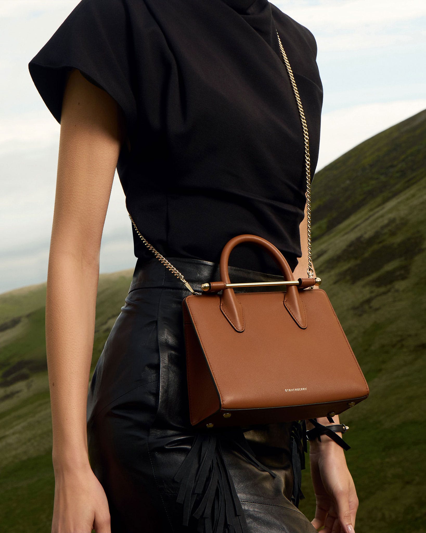 A woman in a black top carrying a brown purse