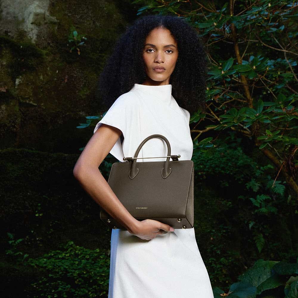 A woman in a white dress holding a brown purse