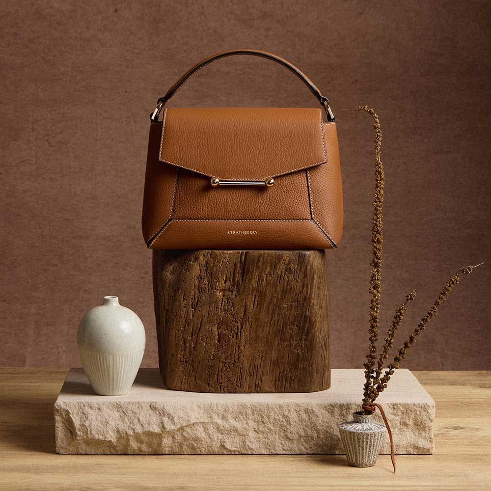 A brown purse sitting on top of a wooden stump